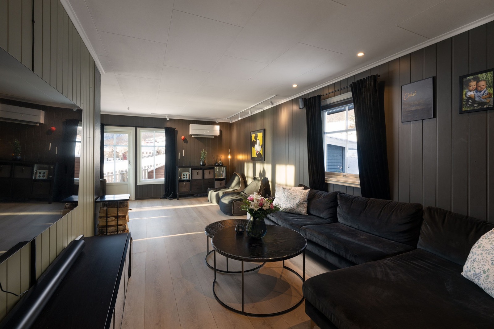 Lun og koselig stue med malte panelplater på vegg, og laminat på gulv. Galleribilde