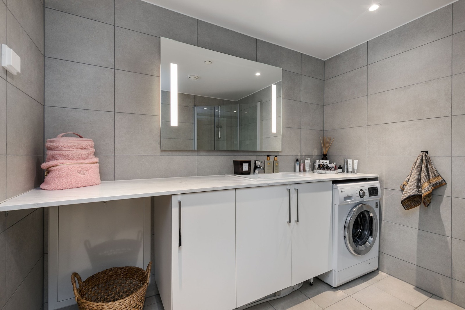 Baderomsinnredning bestående av benkeskap med glatte fronter. Speil og belysning over servant. Galleribilde