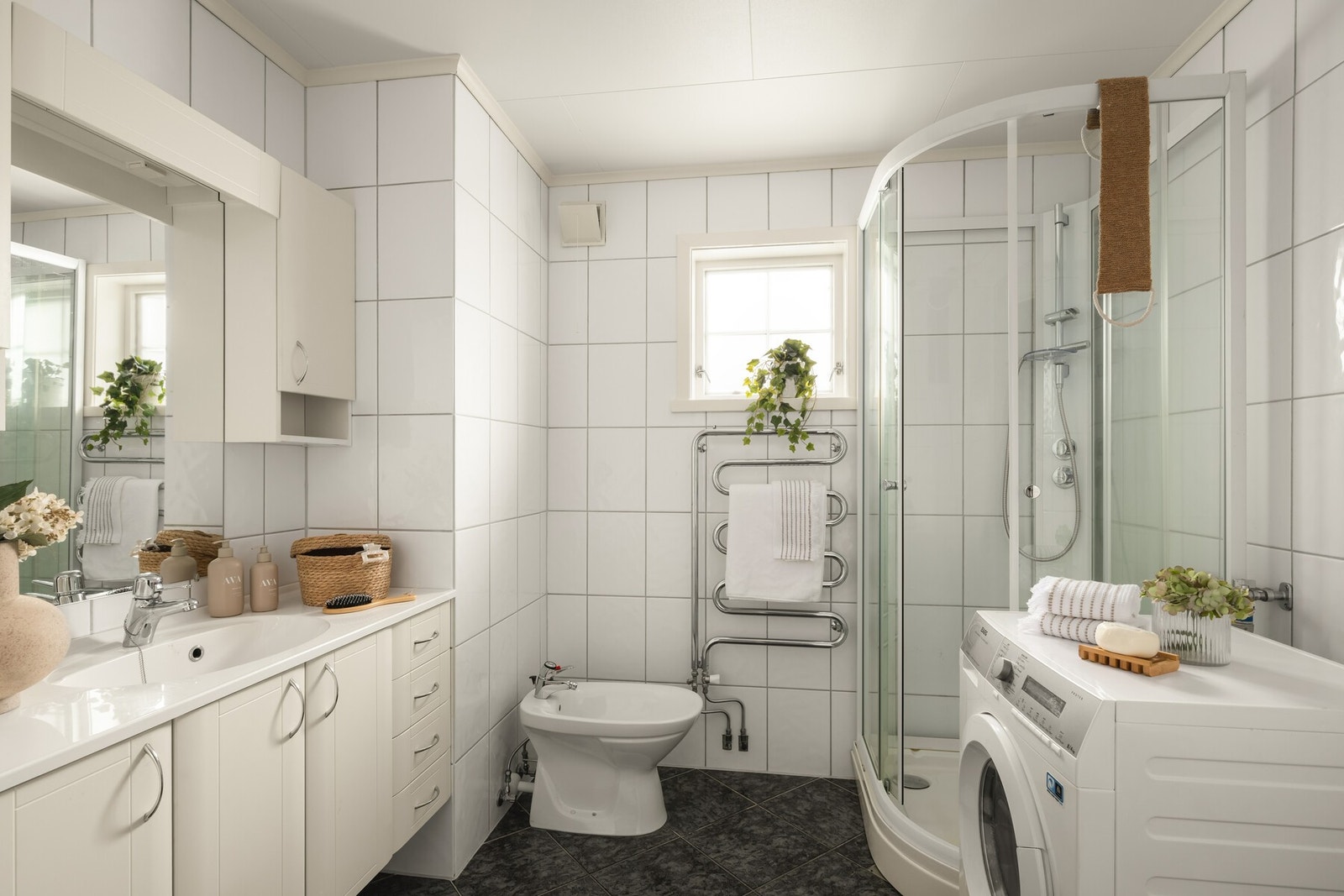 Badet fremstår lyst og pent med flislagte vegger og gulv, elektriske varmekabler. Her finner du bidé, toalett, dusjkabinett og opplegg for vaskemaskin - alt på ett praktisk og funksjonelt sted. Galleribilde