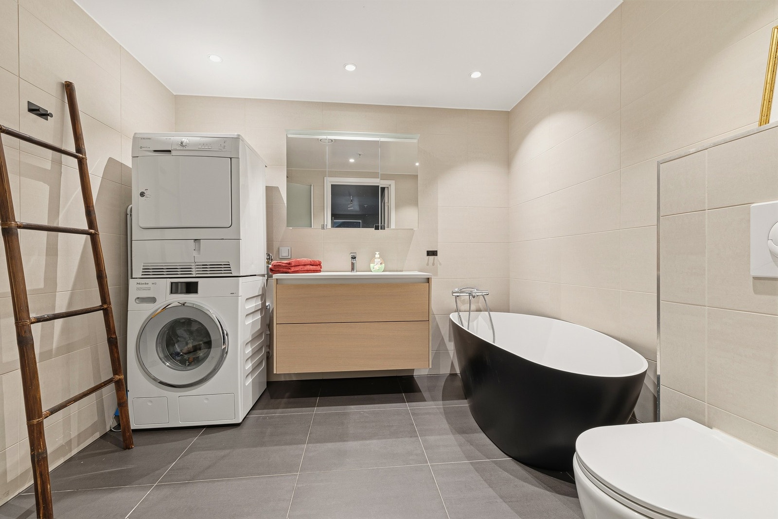 Hovedbad innredet med toalett, badekar, dusj og servant med skuffeseksjon og speilskap. Galleribilde