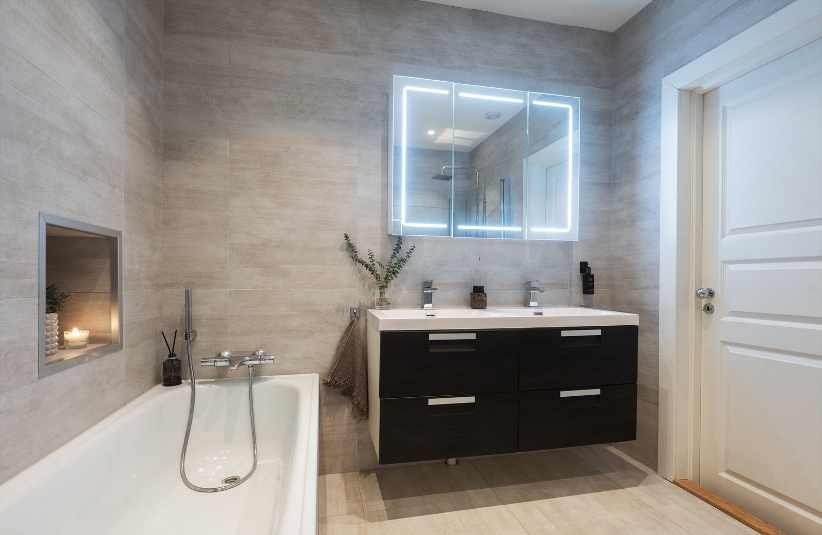 Badet innredet med både dusjhjørne med innfellbare glassdører og badekar med en praktisk nisje. Galleribilde