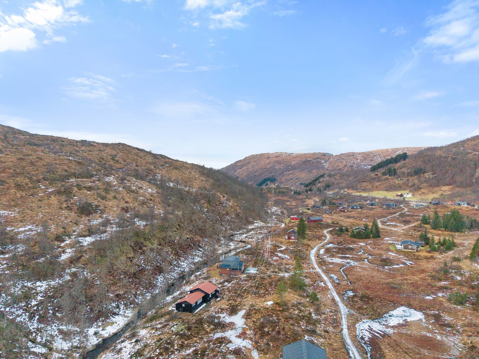 Dronebilde mot vest. Den store parkeringsplassen for hyttene ligger langs veien til høyre på bildet. Galleribilde