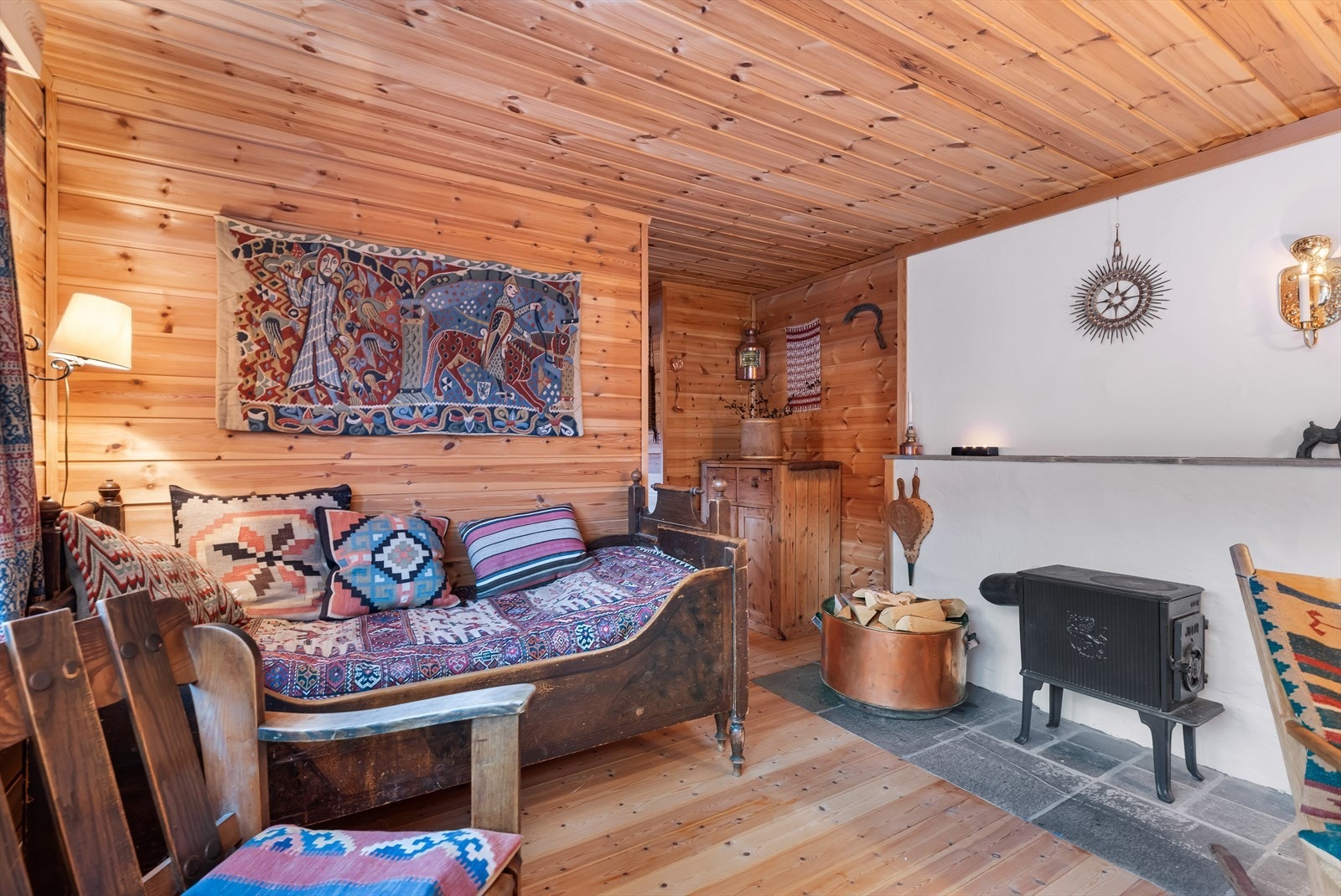 Oppvarmingen i hytten kommer fra en solid vedovn som er sentralt plassert i rommet. Galleribilde