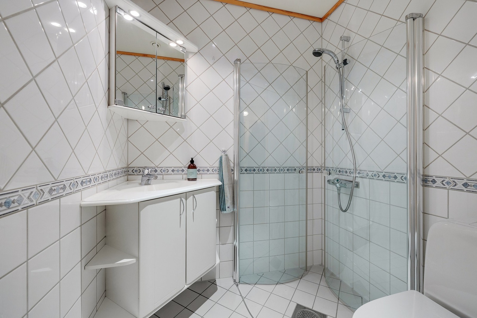 Bad nr. 2 er pent flislagt og har vannbåren gulvvarme, gulvstående toalett og vegghengt servant på servantskap. Videre er det vegghengte dusjdører i glass. Galleribilde