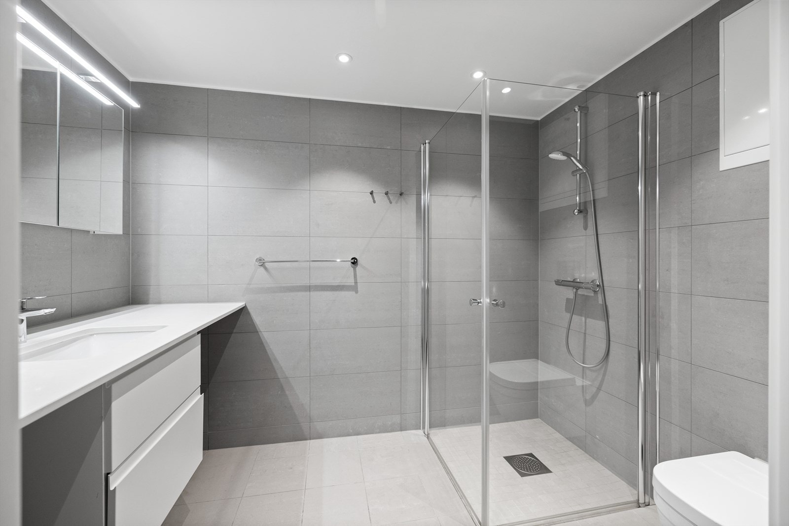 Badet er flott og delikat med dusj på vegg med innfellbare glassdører Galleribilde