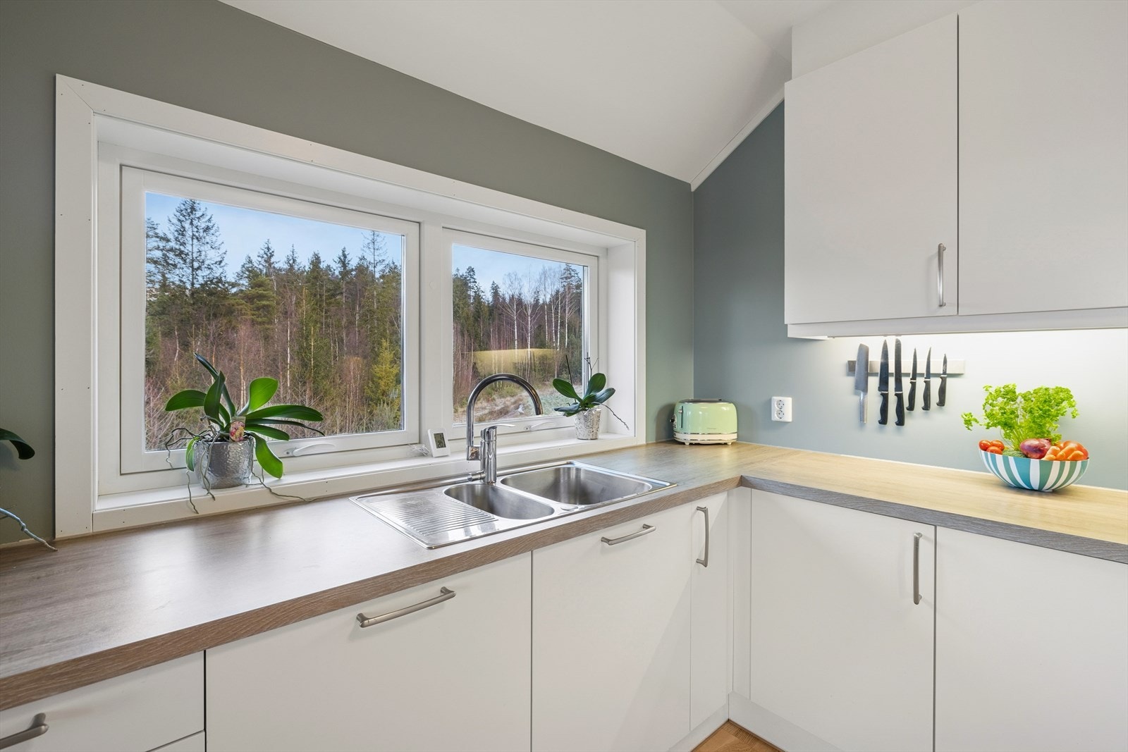 Innredning med malte glatte fronter og laminat benkeplate med utslagsvask og blandebatteri. Galleribilde