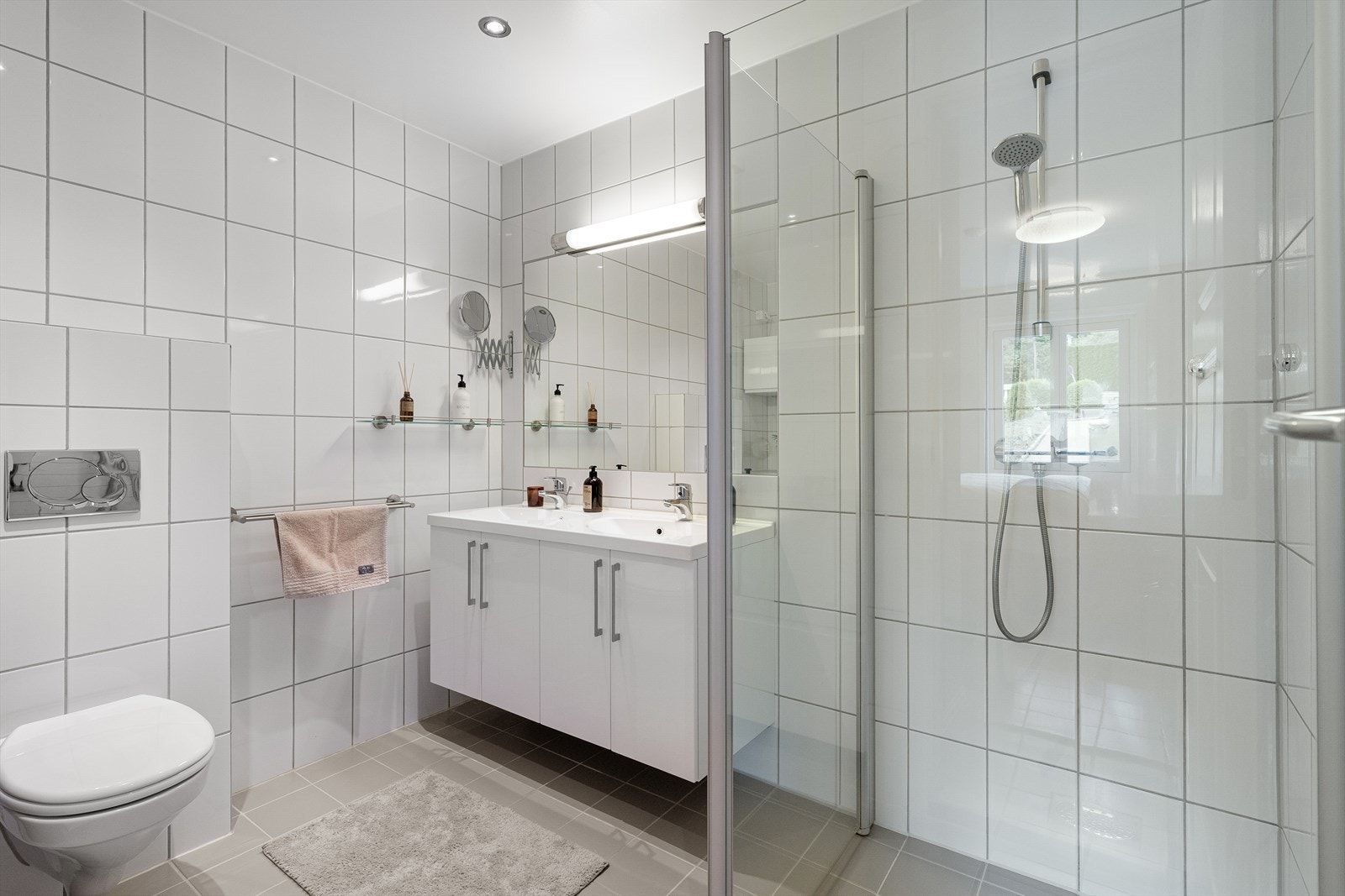 Vegghengt toalett og dusjhjørne med innfellbare glassdører. Baderomsinnredning med to servanter Galleribilde