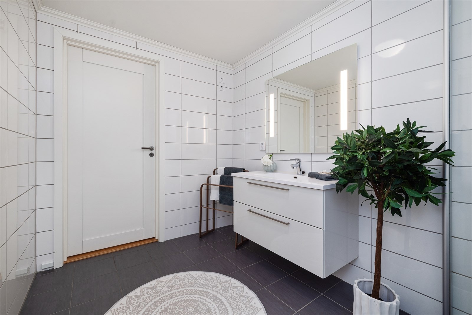 Romslig og moderne baderom med flislagte gulv og vegger i tidløse farger. Galleribilde