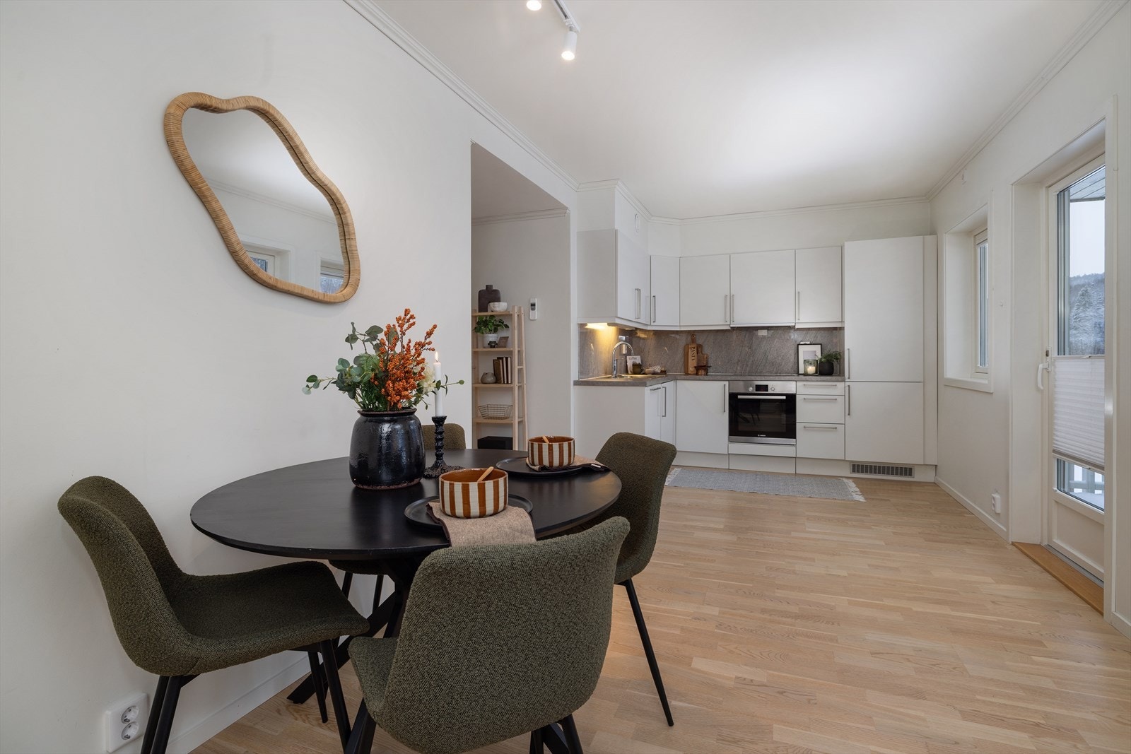 Kjøkkenet er stilrent med hvite, glatte fronter og integrerte hvitevarer. Galleribilde