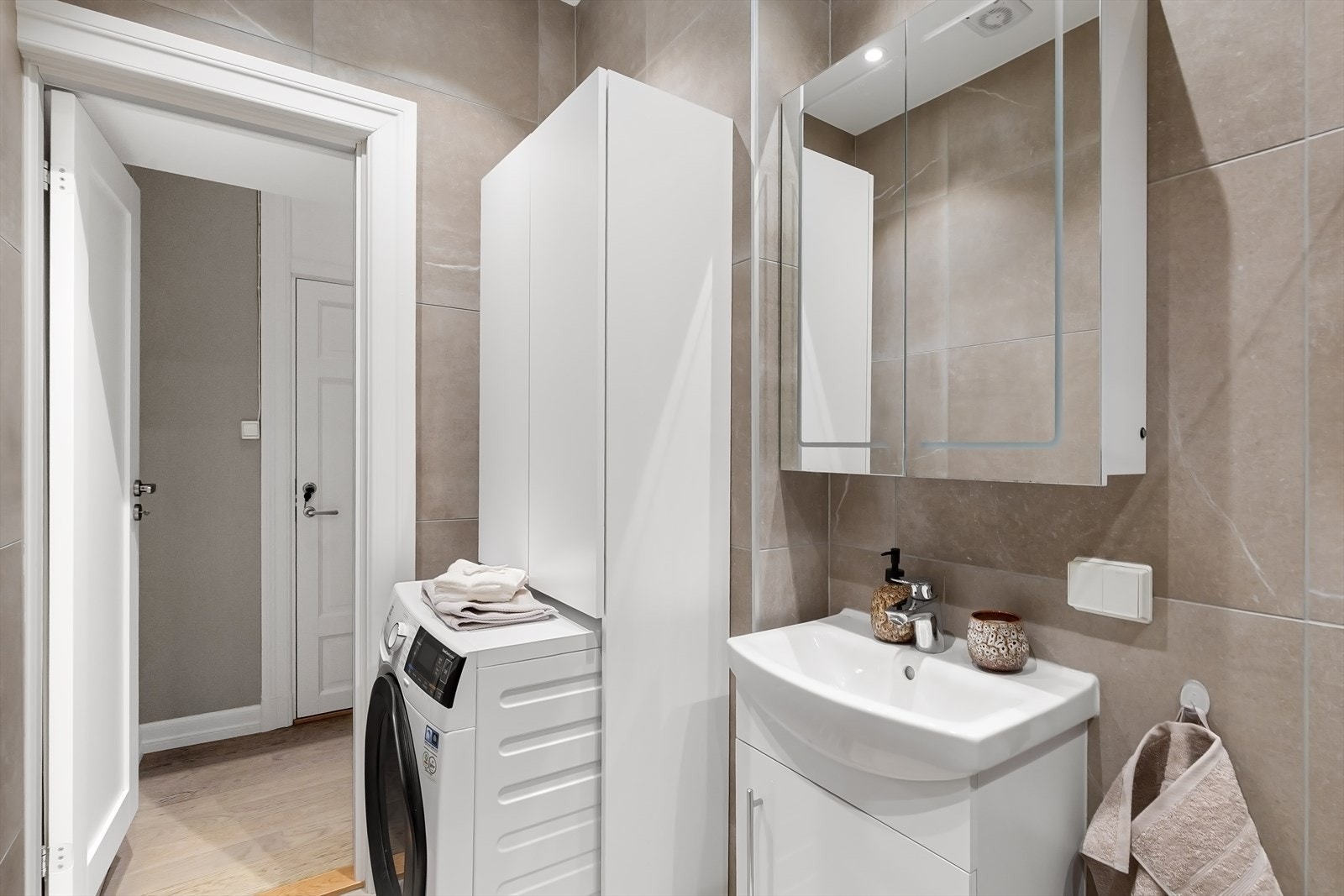 Badet består av flislagt gulv med varmekabler, flislagte vegger og malt himling. Opplegg for vaskemaskin. Galleribilde