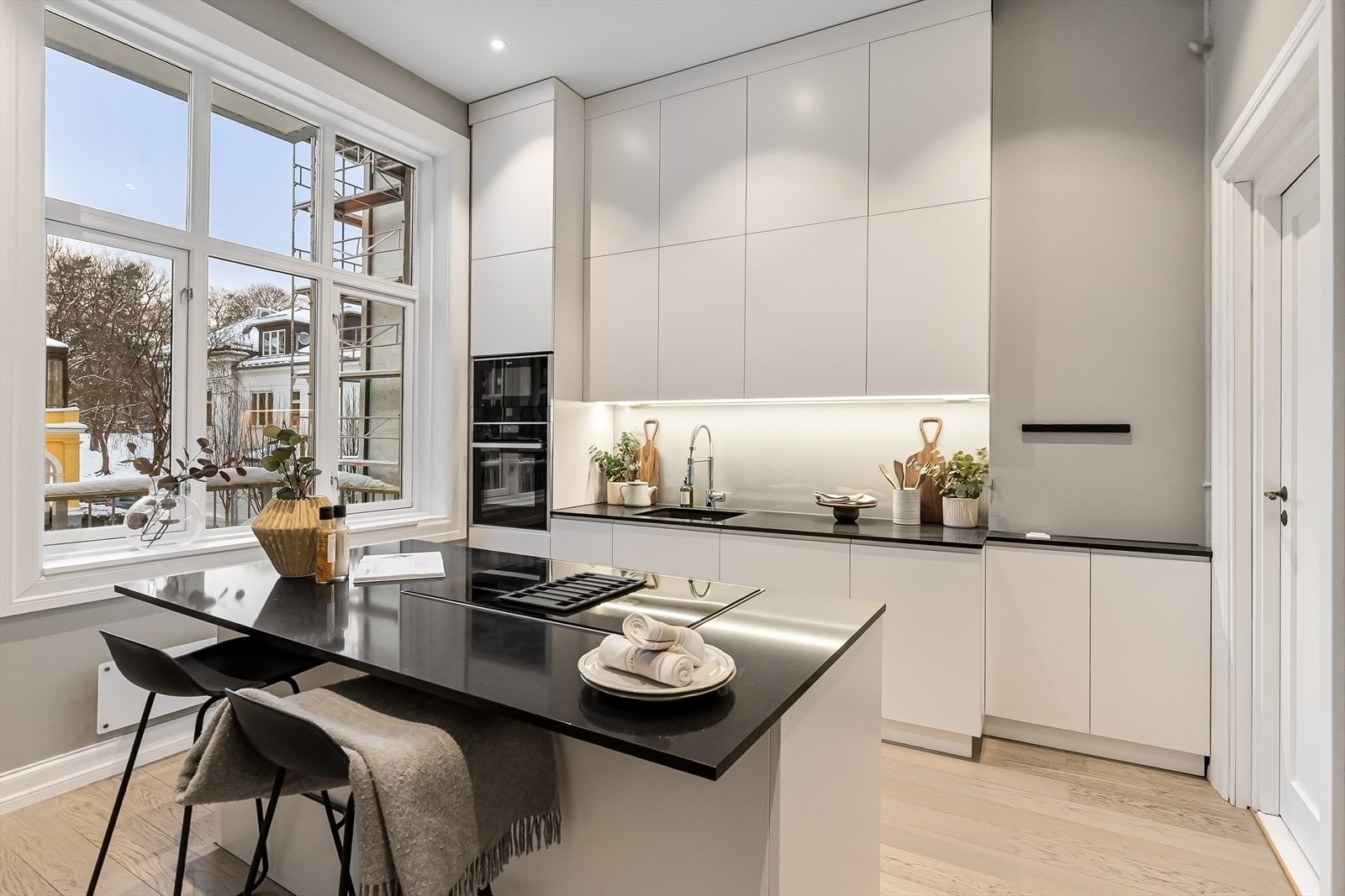 Velutstyrt kjøkken med innredning fra Oslo Kjøkkenstudio fra 2020 med hvite glatte fronter og stein benkeplate. Galleribilde