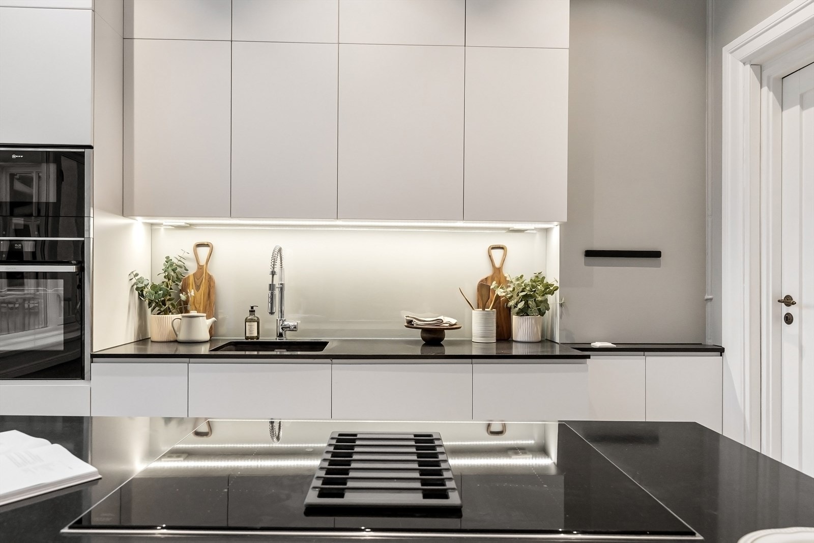 Kjøkkenøy/spisebenk med stein benkeplate med induksjon platetopp. Integrert i kjøkkeninnredningen er stekeovn, vinskap, micro og oppvaskmaskin. Galleribilde