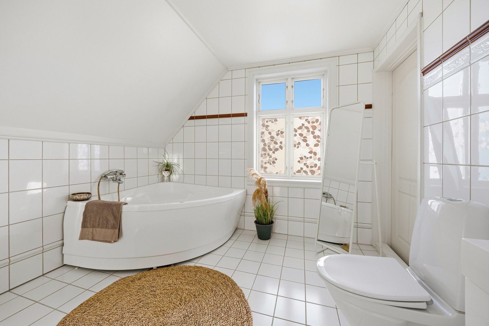 Stort flislagt bad fra byggeår med fliser på gulv og vegger, samt vannbåren gulvvarme. Badet er innredet med vegghengt servantmøbel med dobbel servant og speil med belysning. Galleribilde