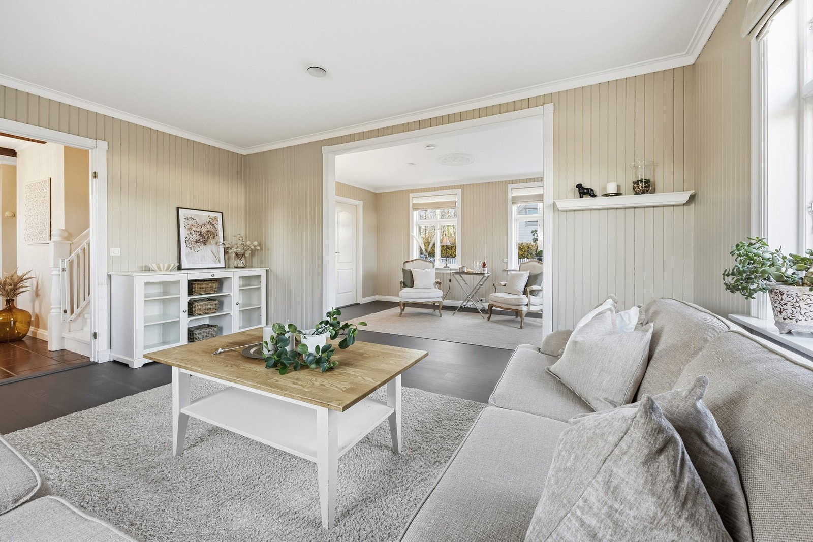 Gulvet er belagt med malt parkett, som strekker seg sømløst videre innover mot stue, spisestue og kjøkken. Mellom rommene er det stilfulle, doble fløydører som gir boligen et elegant preg. Galleribilde