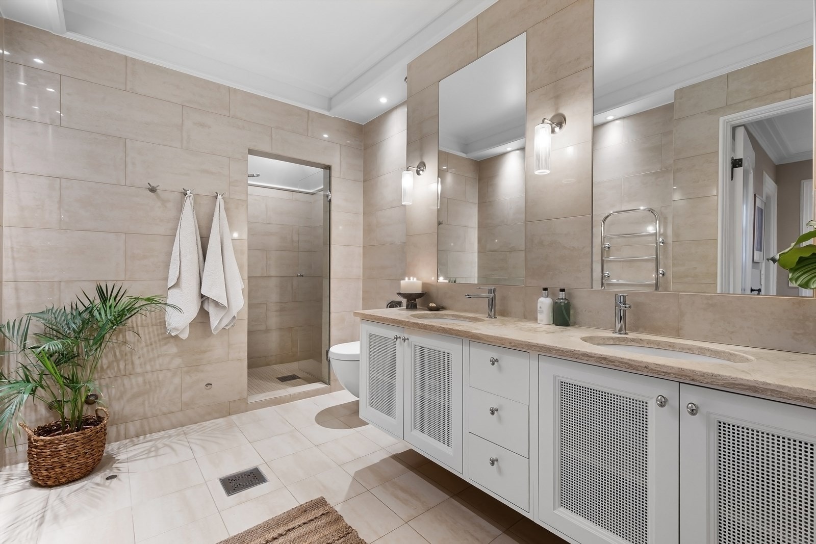 Bad/wc med dusjnisje med skilledør i herdet glass, veggfestet toalett, 2 servanter og innfelt speil over servanter. Opplegg for badekar i hjørnet til venstre. Galleribilde