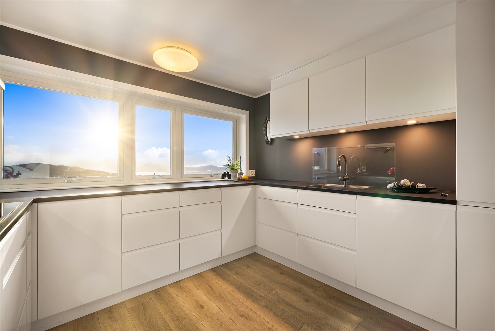 Slette, hvite fronter, laminat benkeplate, integrert stekeovn, kjøl- og fryseskap, platetopp og oppvaskmaskin Galleribilde