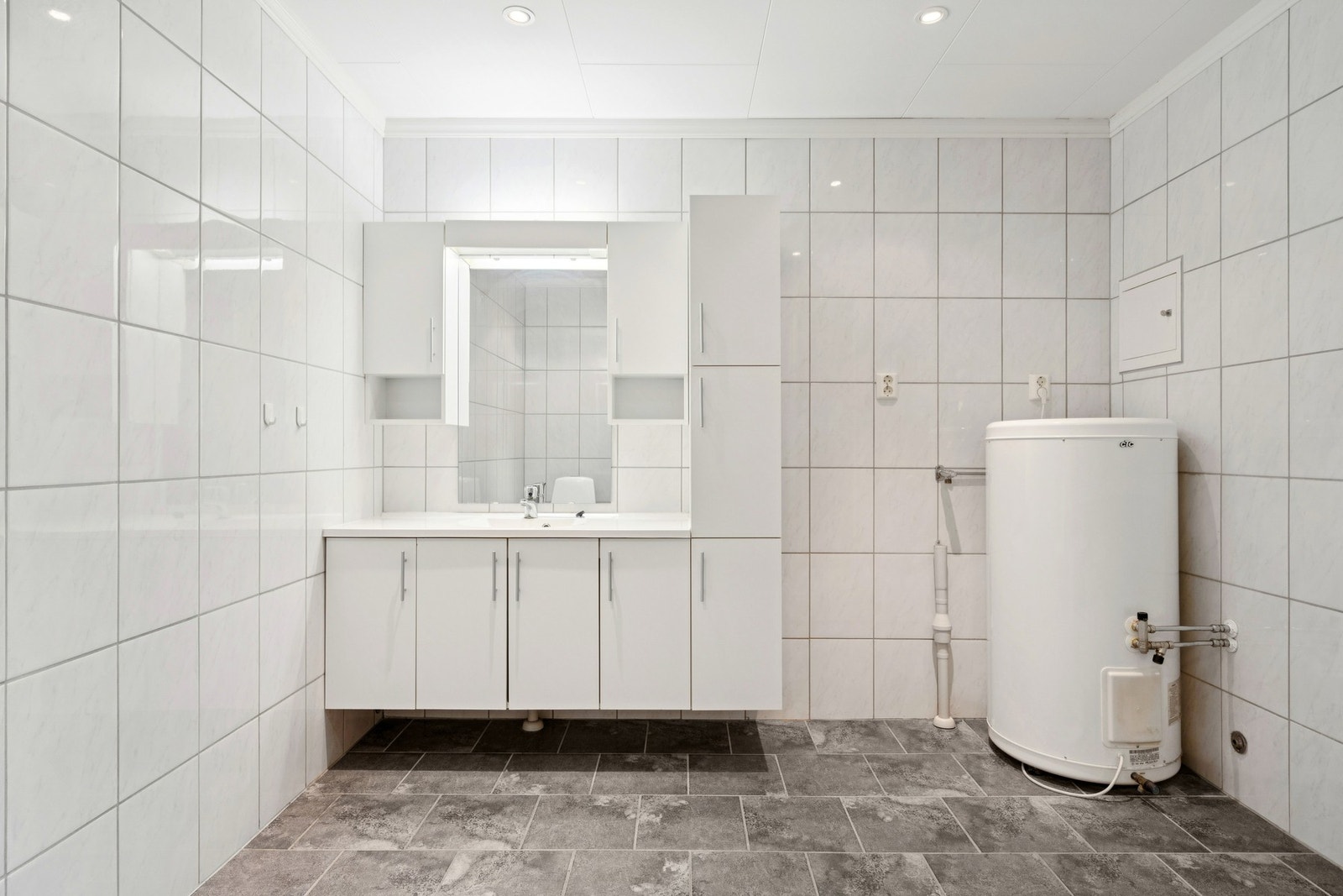 Badet har varmekabler i gulv, godt med belysning, uttak for vaskemaskin og dusjhjørne Galleribilde