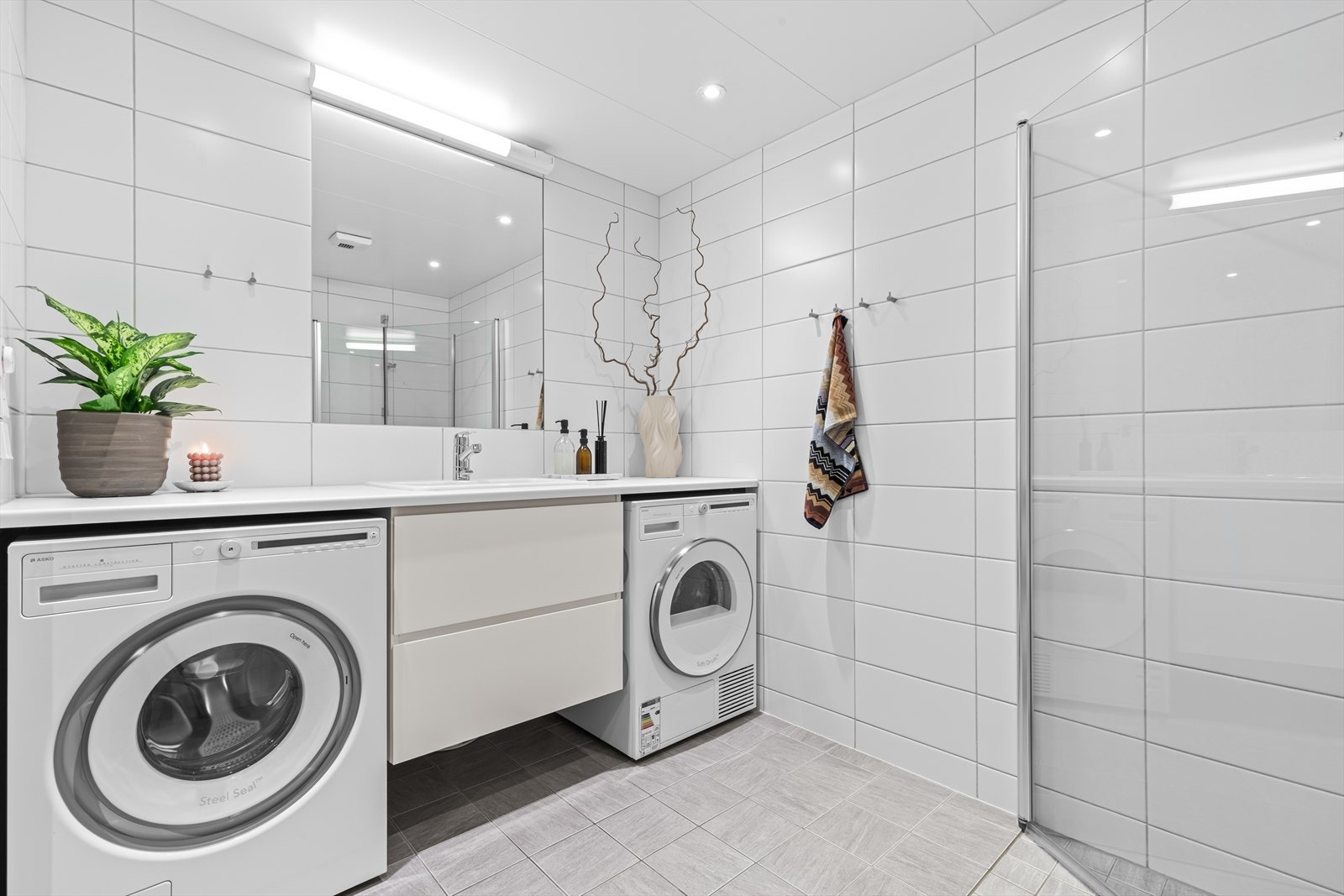 Innredningen består av servantskap med skuffeseksjon, speil, vegghengt toalett og dusjhjørne med svingdører. Galleribilde