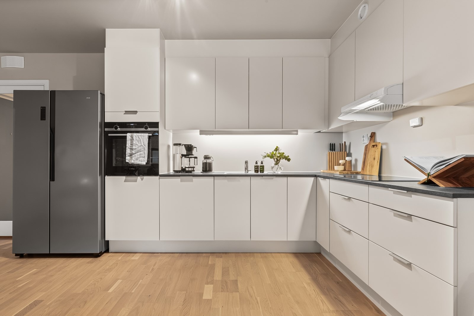 Kjøkkenet er velutstyrt med integrerte hvitevarer som induksjonstopp, stekeovn og oppvaskmaskin, samt plass til frittstående kombi kjøle- og fryseskap. Galleribilde