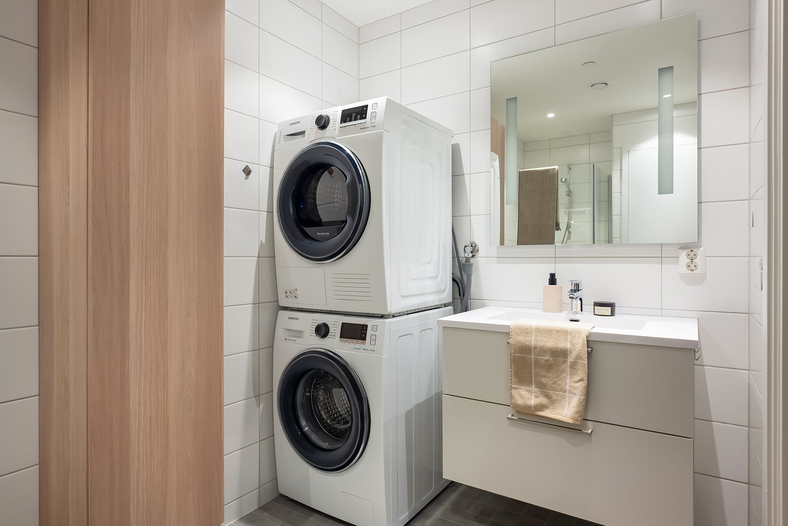 Badet har opplegg for vaskemaskin, god skapplass i servantinnredningen og speil med integrert belysning. Galleribilde