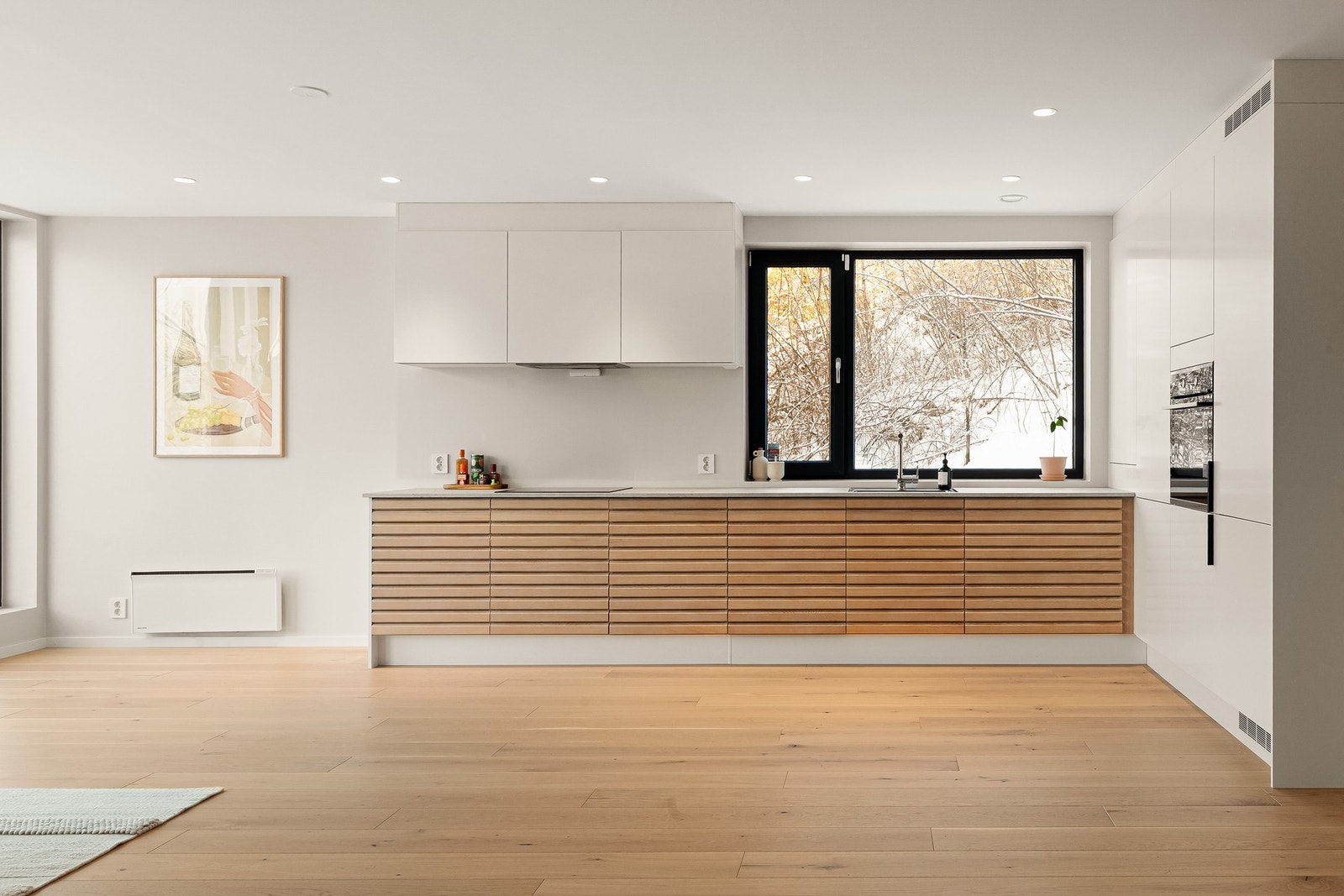 Lekker kontrast med eik lamellfronter, og noe av innredningen som nærmest "smelter" inn i veggen, så kjøkkenet ikke oppleves som et stort møbel. Galleribilde