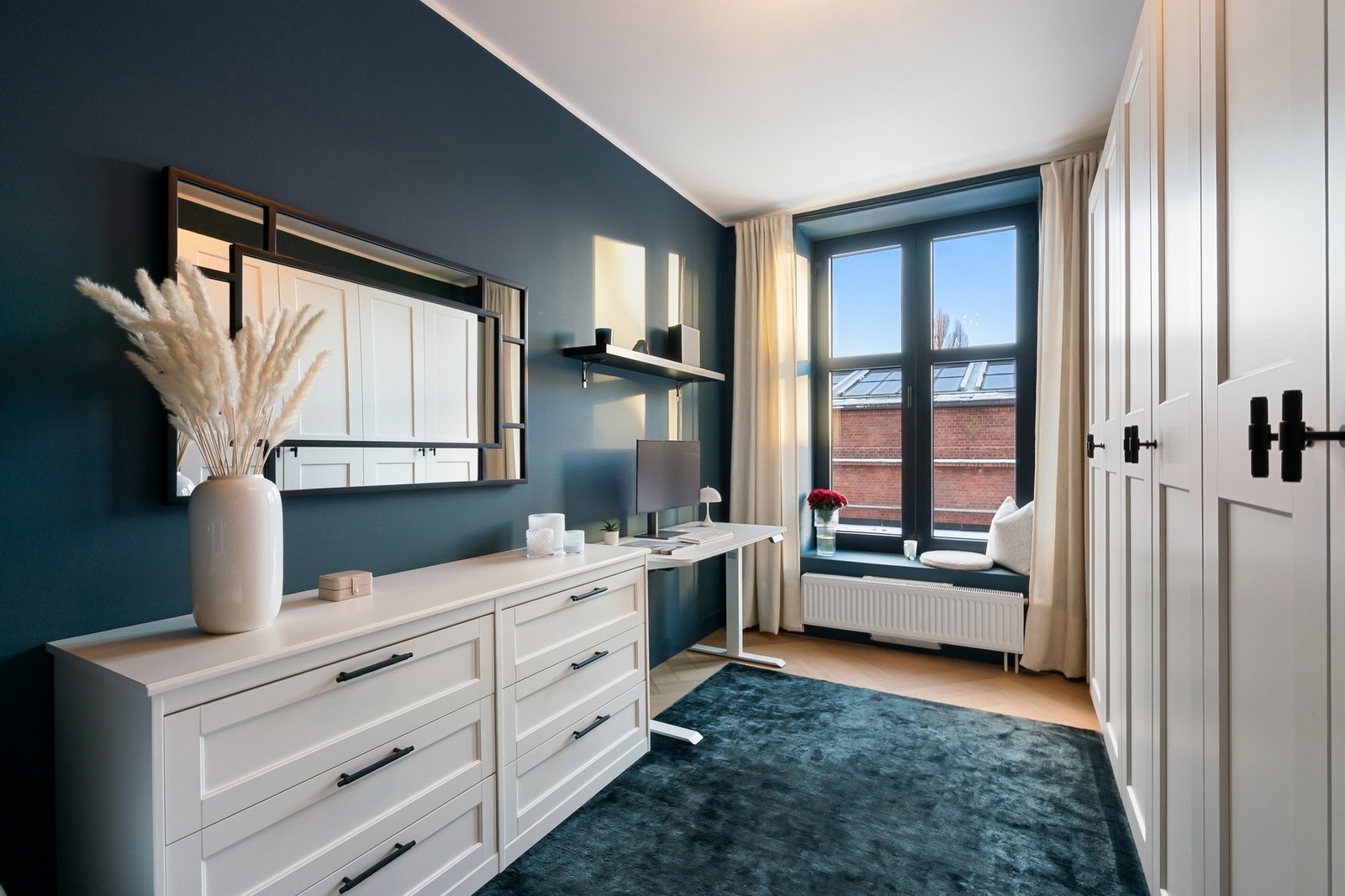 Rommets utforming og innredning gjør at man har plass til både dobbeltseng, ekstra kommode, skrivebord/kontorplass og hele tre doble garderobeskap. På gulvet har man bred fiskebensparkett i eik som er lagt med nedfelt terskel mellom rommene. Galleribilde