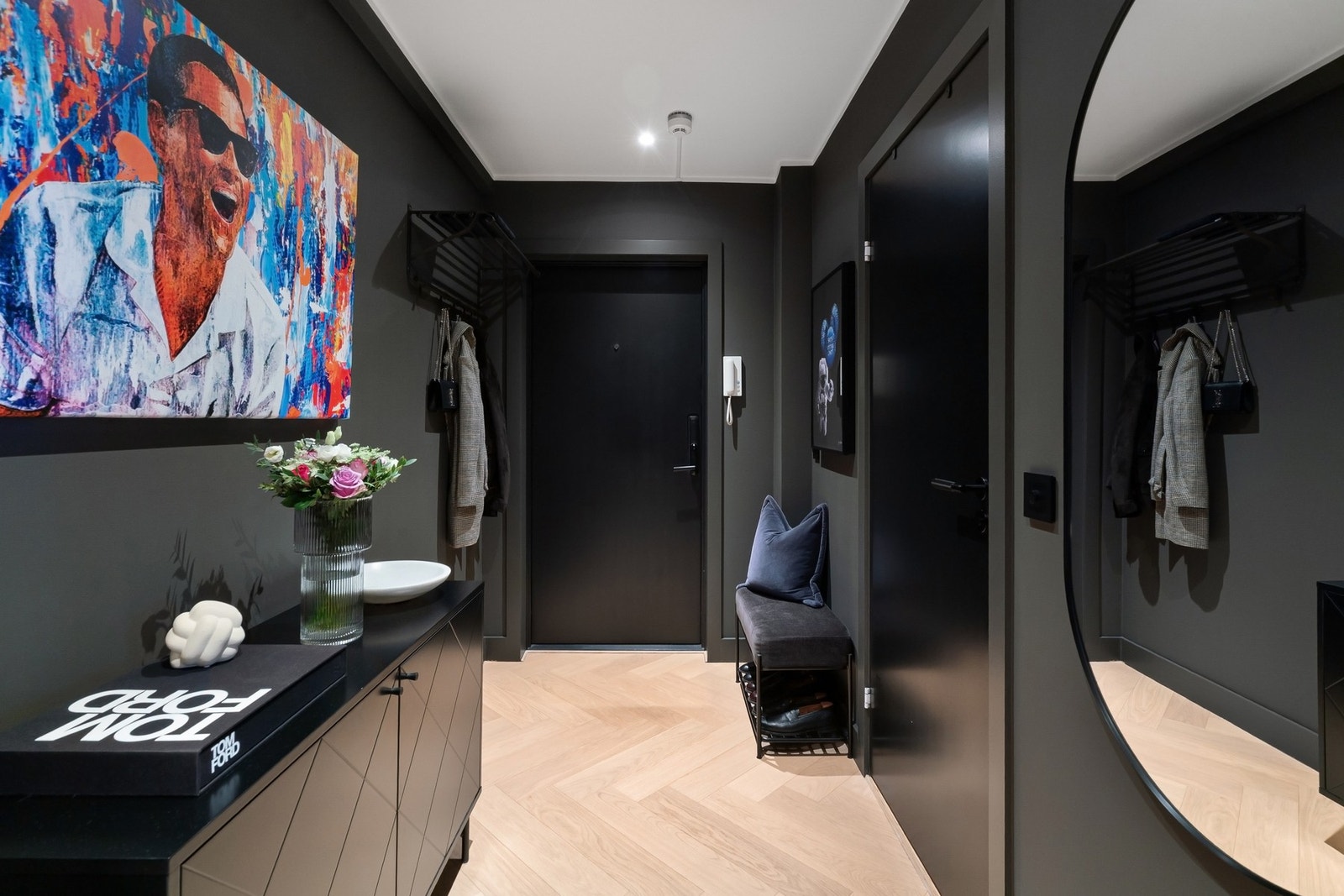 LED-downlights med Elko Plus dimmer og brytere i sort gir fleksibelt og behagelig lys. Det er elektronisk dørlås fra Yale Doorman og dørtelefon med calling anlegg. Sikringsskap med jordfeilautomater er elegant skjult bak en bilderamme ved døren. Galleribilde