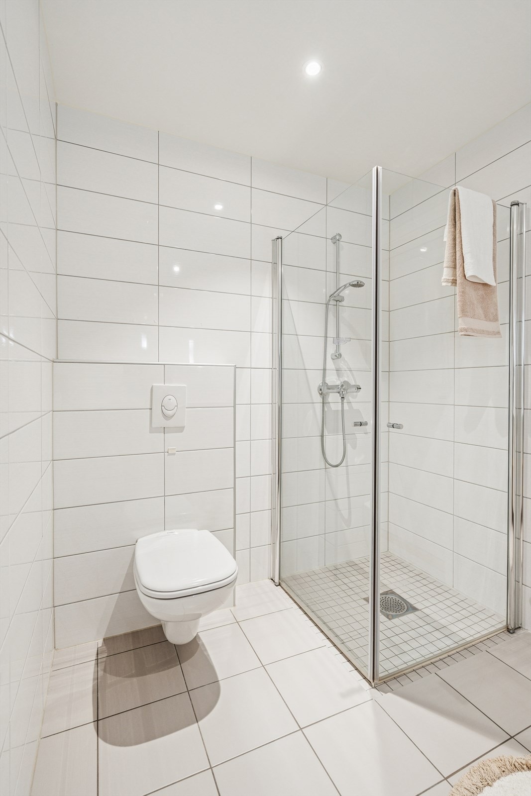 I tillegg er det belyst speil montert på vegg, vegghengt toalett, spotbelysning i taket og en stor dusjsone med innfellbare glassdører. Galleribilde