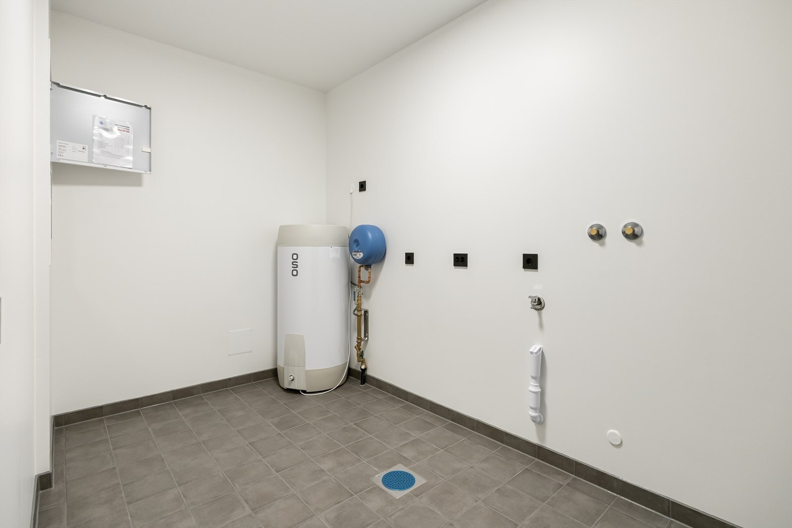 Vaskerom/teknisk rom i underetasjen med fliser på gulv. Rommet har opplegg for vaskemaskin. Galleribilde