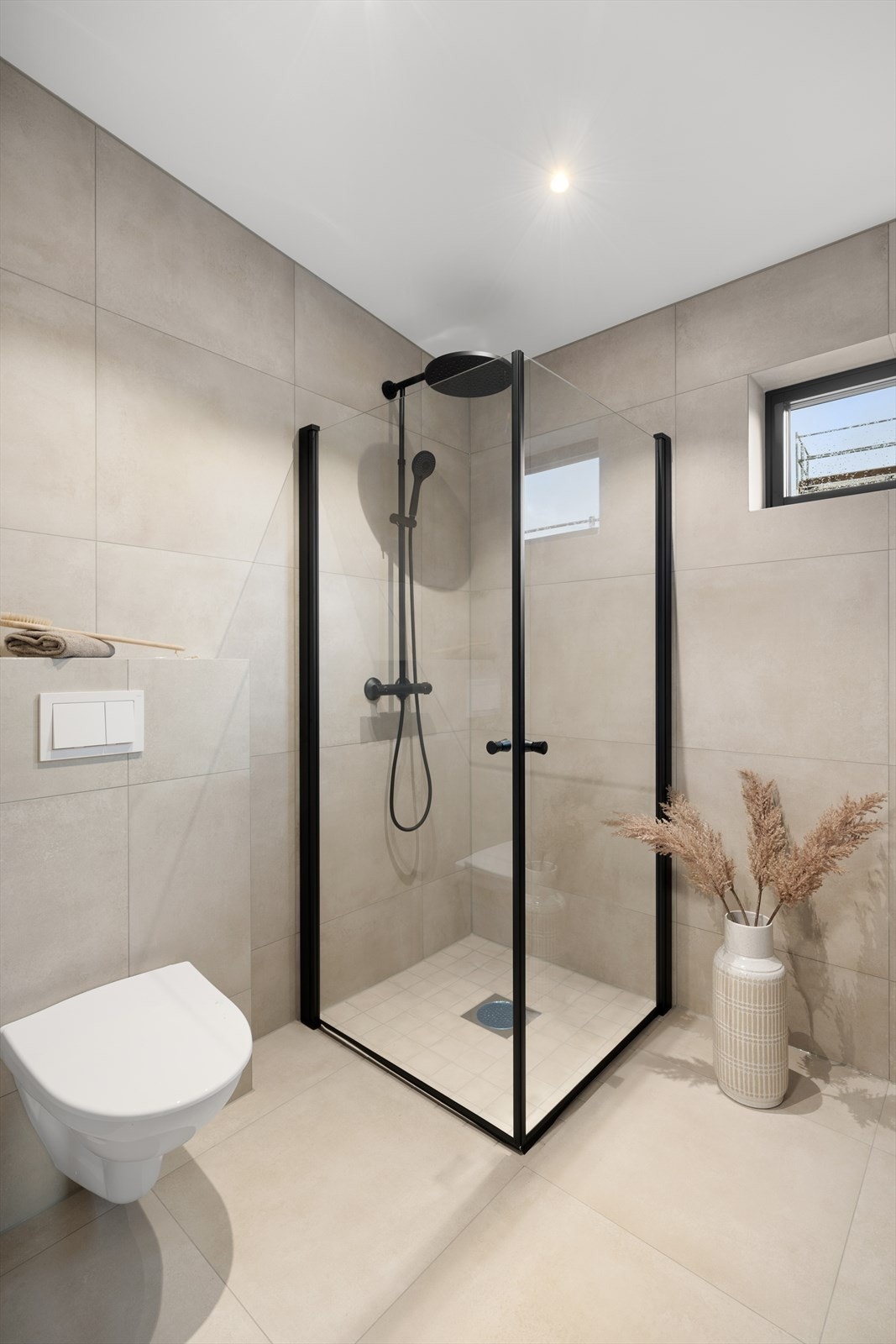 Badet er innredet med dusjhjørne, vegghengt toalett og servant i baderomsinnredning fra Foss Bad. Galleribilde