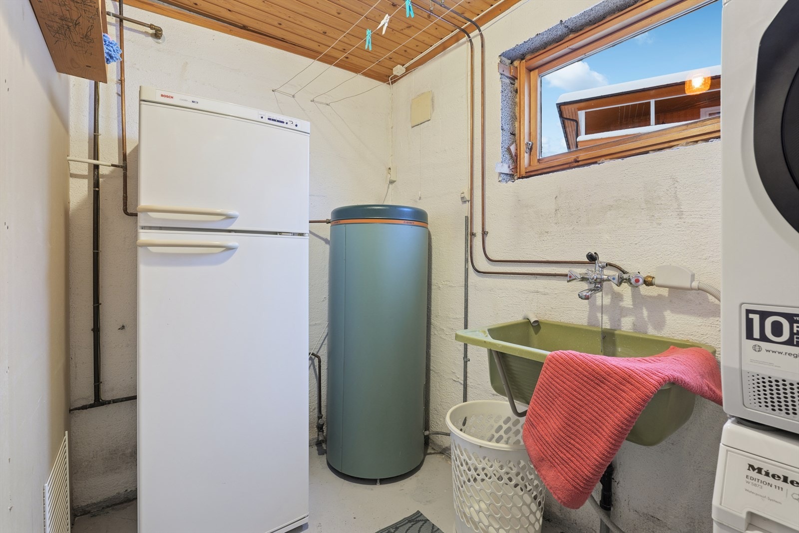 Eldre vaskerom med plass til både vaskemaskin, tørketrommel og oppbevaring. Galleribilde