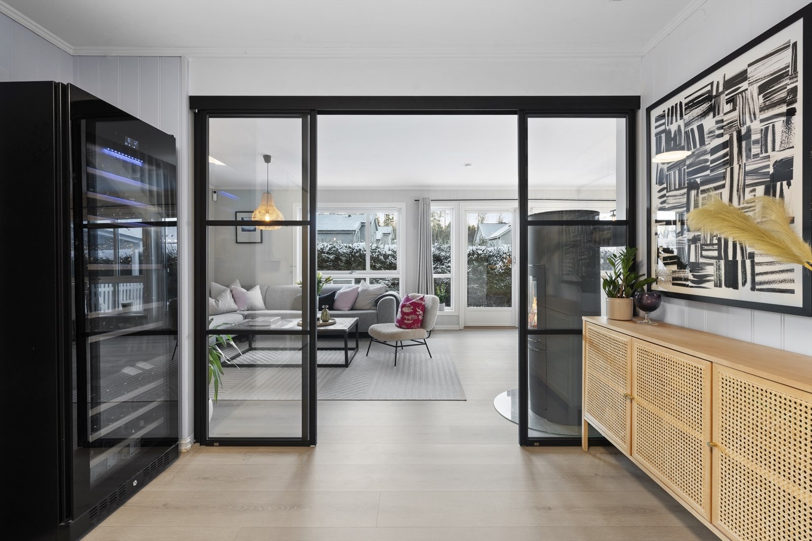 Mellom hallen og stuen er det montert en moderne glasskyvedør i sortlakkert aluminium som effektivt skiller sonene samtidig som lyset får flyte fritt gjennom etasjen. Galleribilde