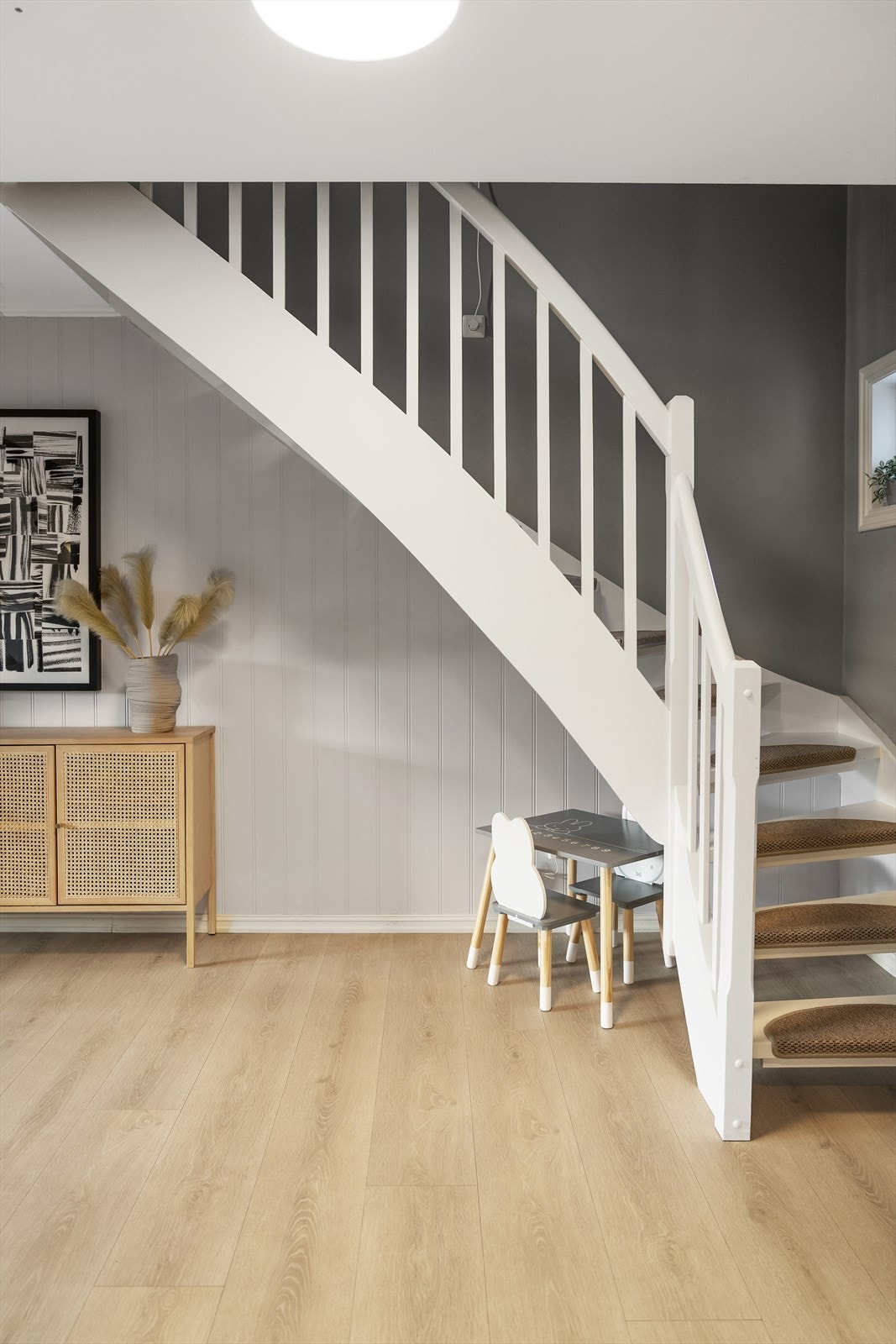 En hvitmalt tretrapp leder opp til andre etasje, hvor alle boligens fire soverom er praktisk samlet. Galleribilde