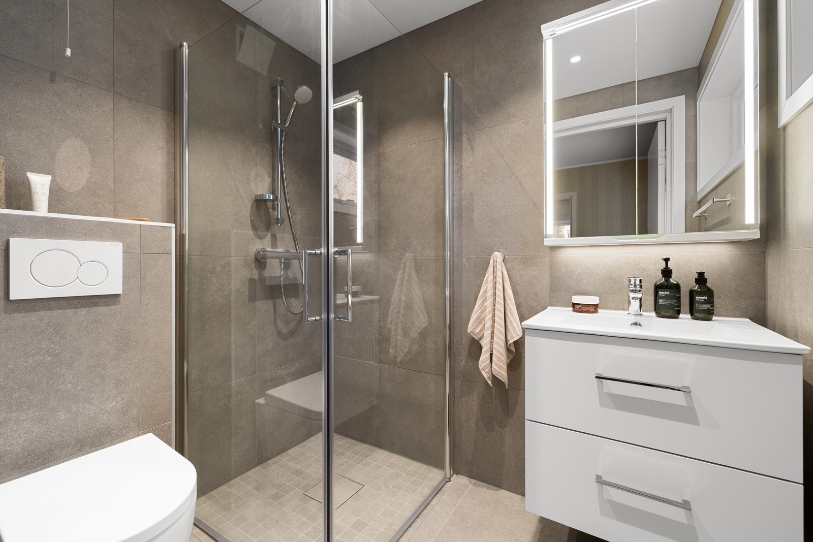 Boligen har to lekre bad som begge ble totalrenovert i 2024. Rommet er utstyrt med nedfelt servant, veggmontert toalett og dusjhjørne med dusjvegger i glass - en smart og plassbesparende løsning. Galleribilde