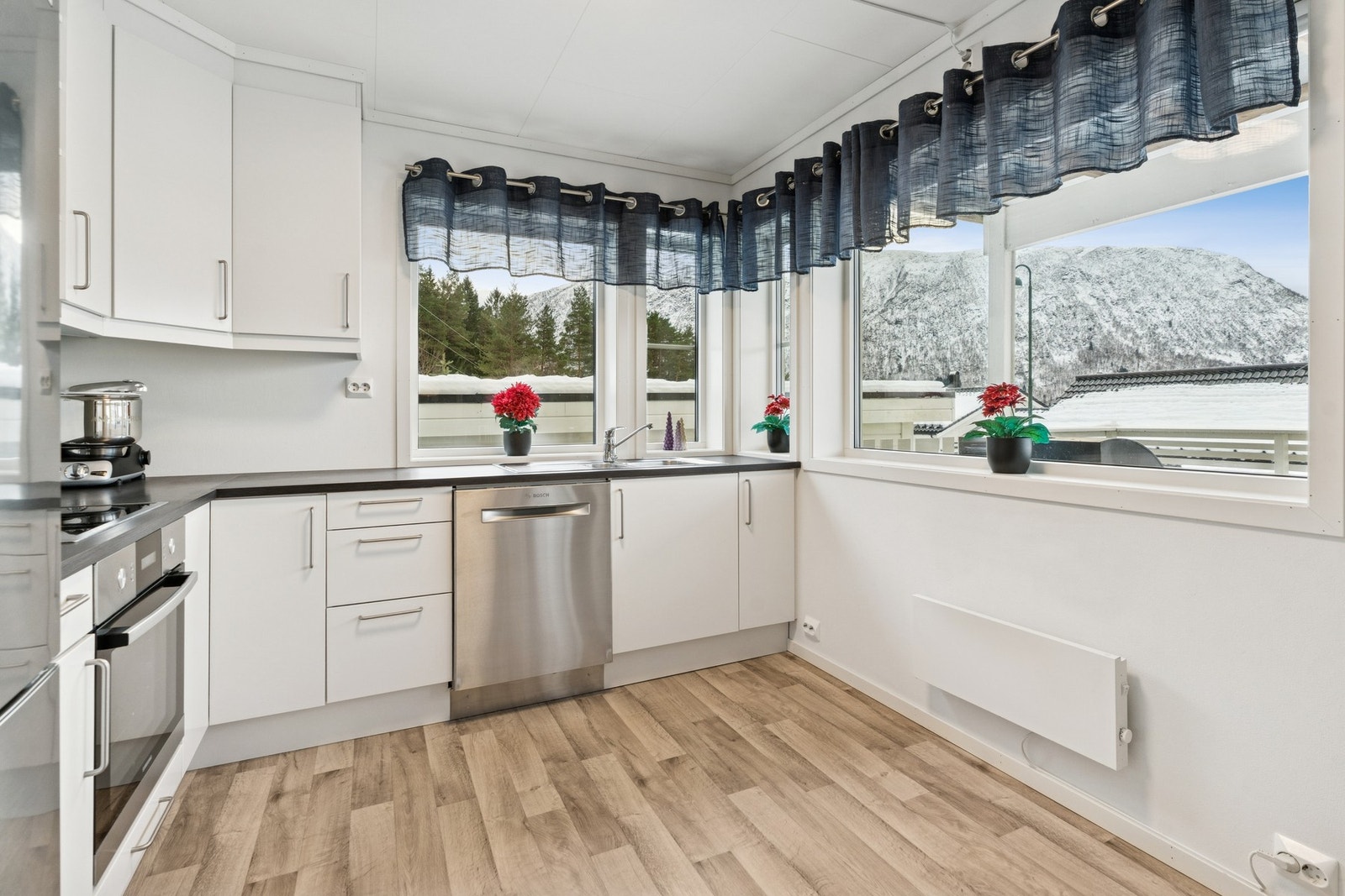 Hvitt kjøkken med glatte skapfronter fra byggeåret og takhøye overskap. Galleribilde