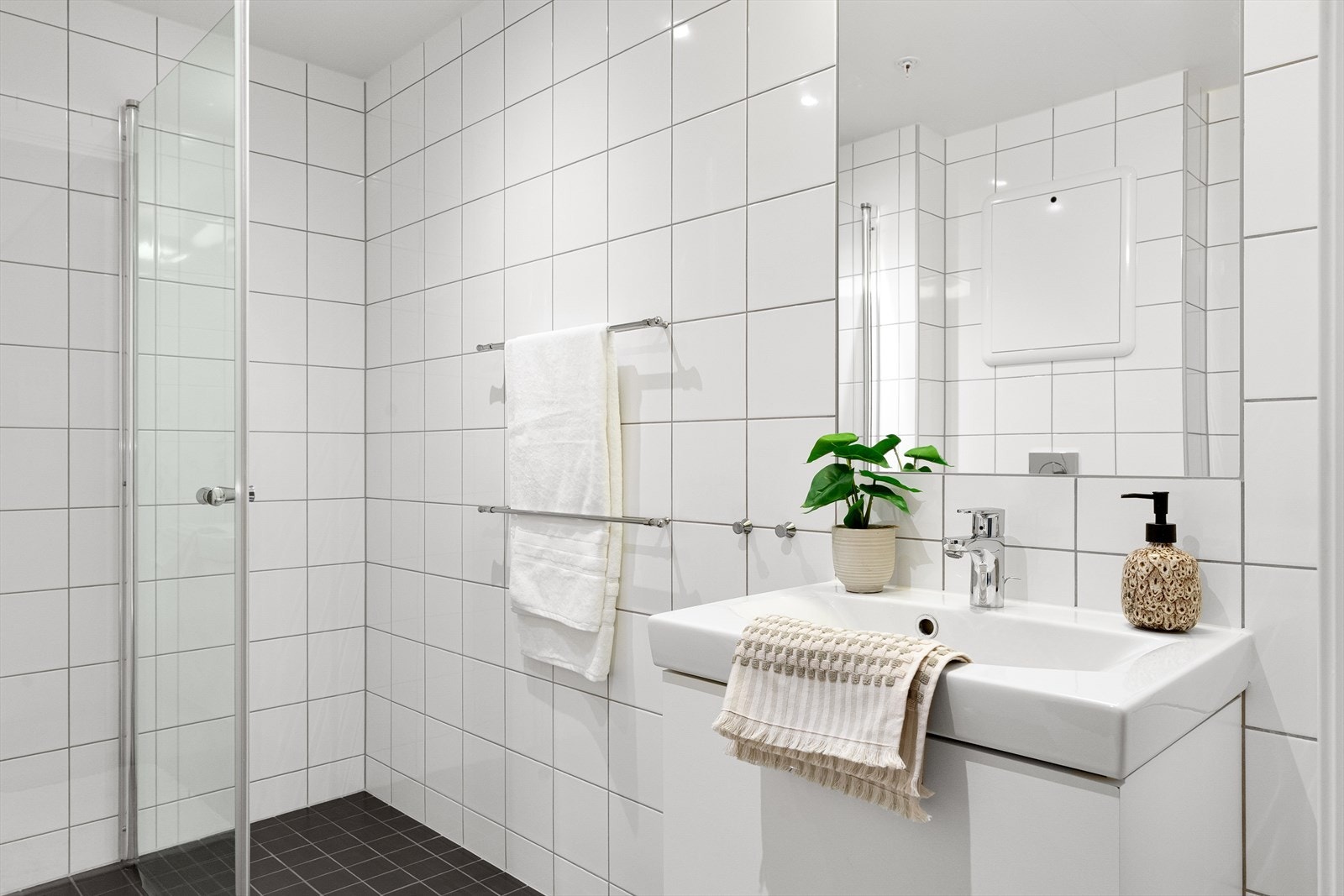 Baderom med innfelte downlights, vegghengt klosett, nedfelt servant i innredningen, dusjhjørne med glassdører, opplegg for vaskemaskin og balansert ventilasjon. Galleribilde