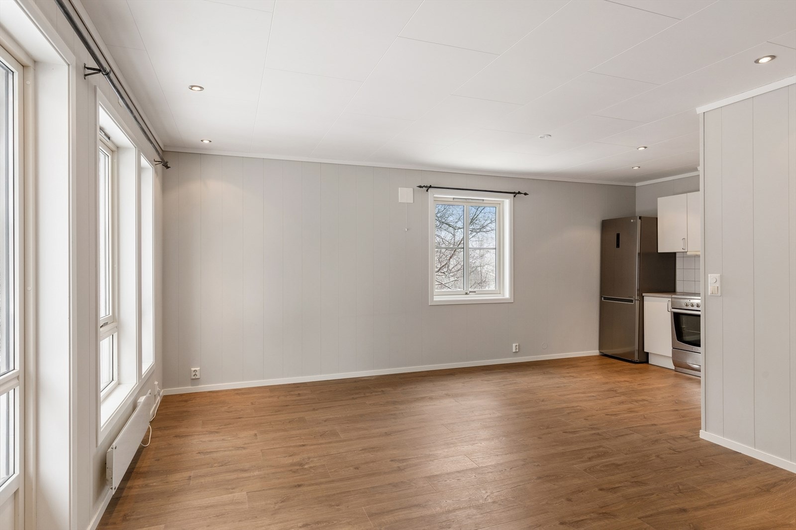 Stuen fremstår som et lyst og innbydende oppholdsrom med en åpen løsning mot kjøkkenet, noe som skaper en sosial og romslig atmosfære. Galleribilde