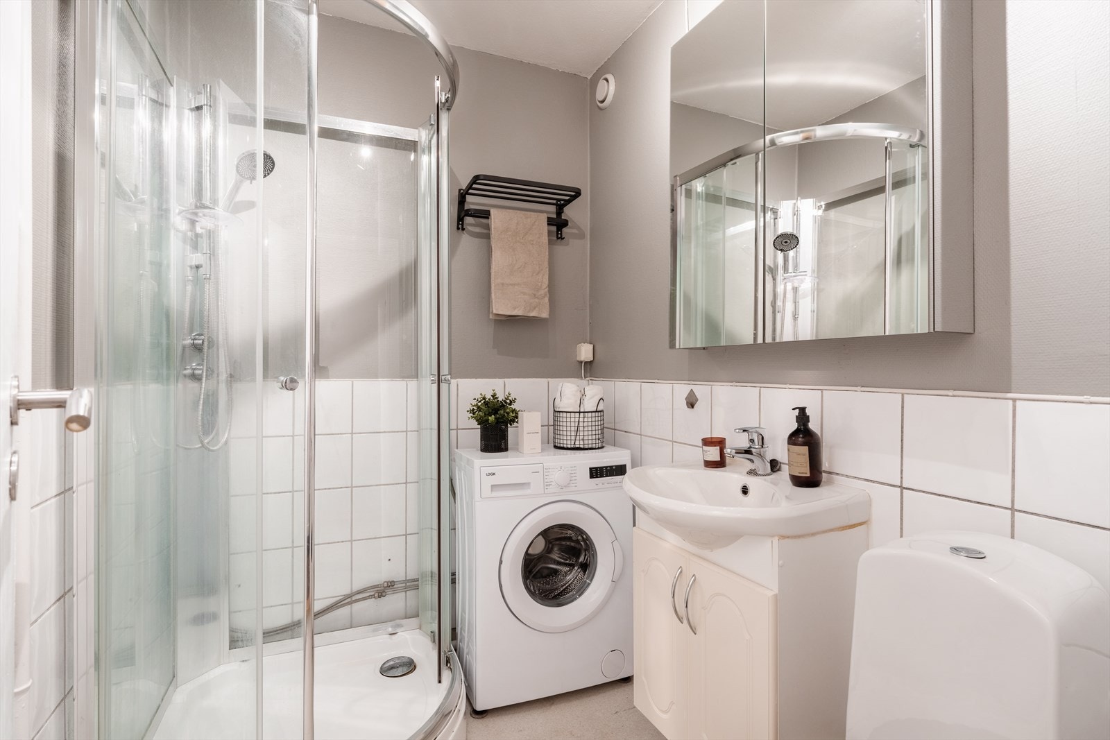 Romslig og lyst baderom med opplegg for vaskemaskin. Galleribilde