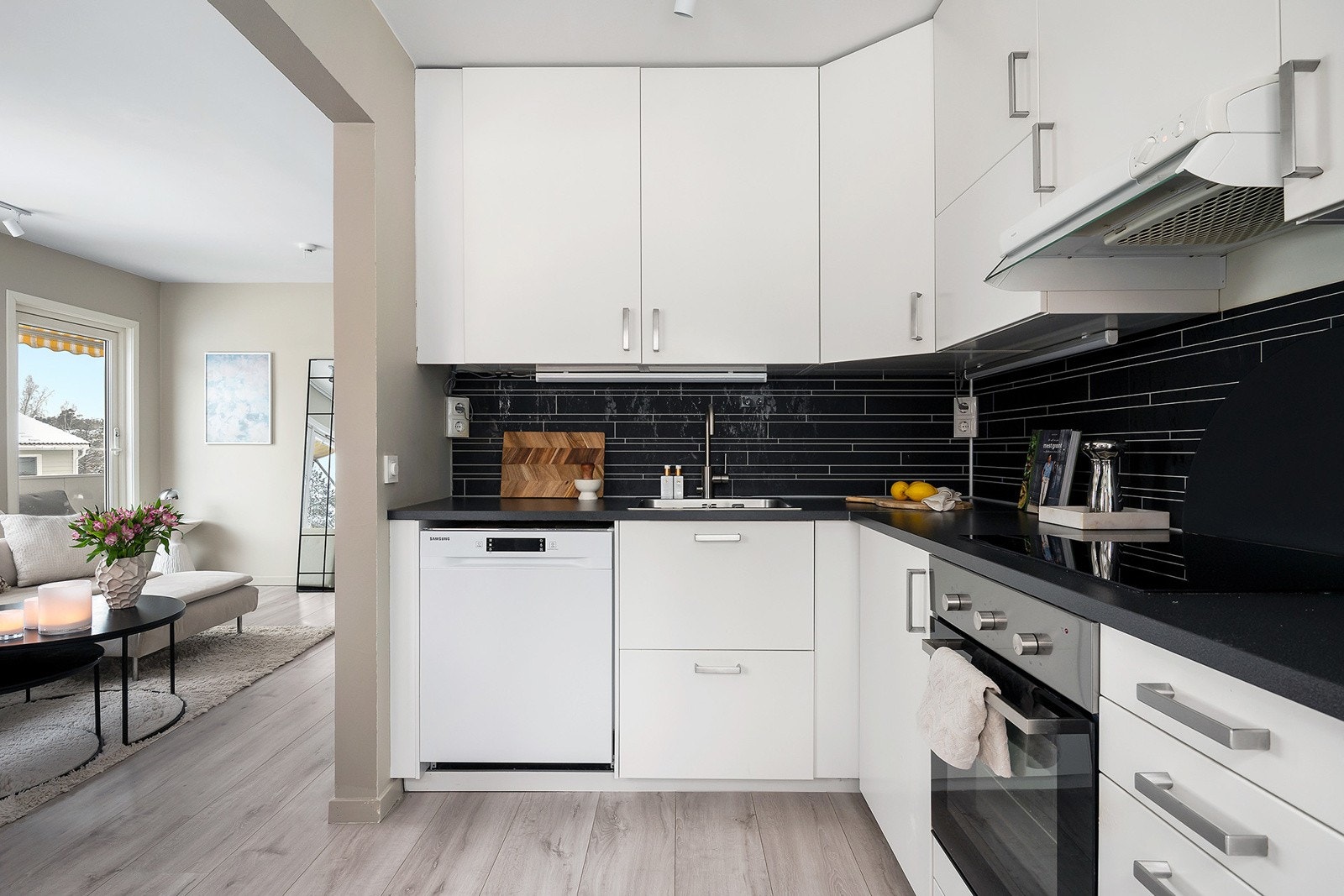 Kjøkkeninnredning med glatte folierte skapfronter, laminat benkeplate med sprutplate på bakvegg, enkel oppvaskkum, ventilator og innfelte hvitevarer som koketopp, stekeovn, frittstående oppvaskmaskin, kjøl/- fryseskap. Galleribilde