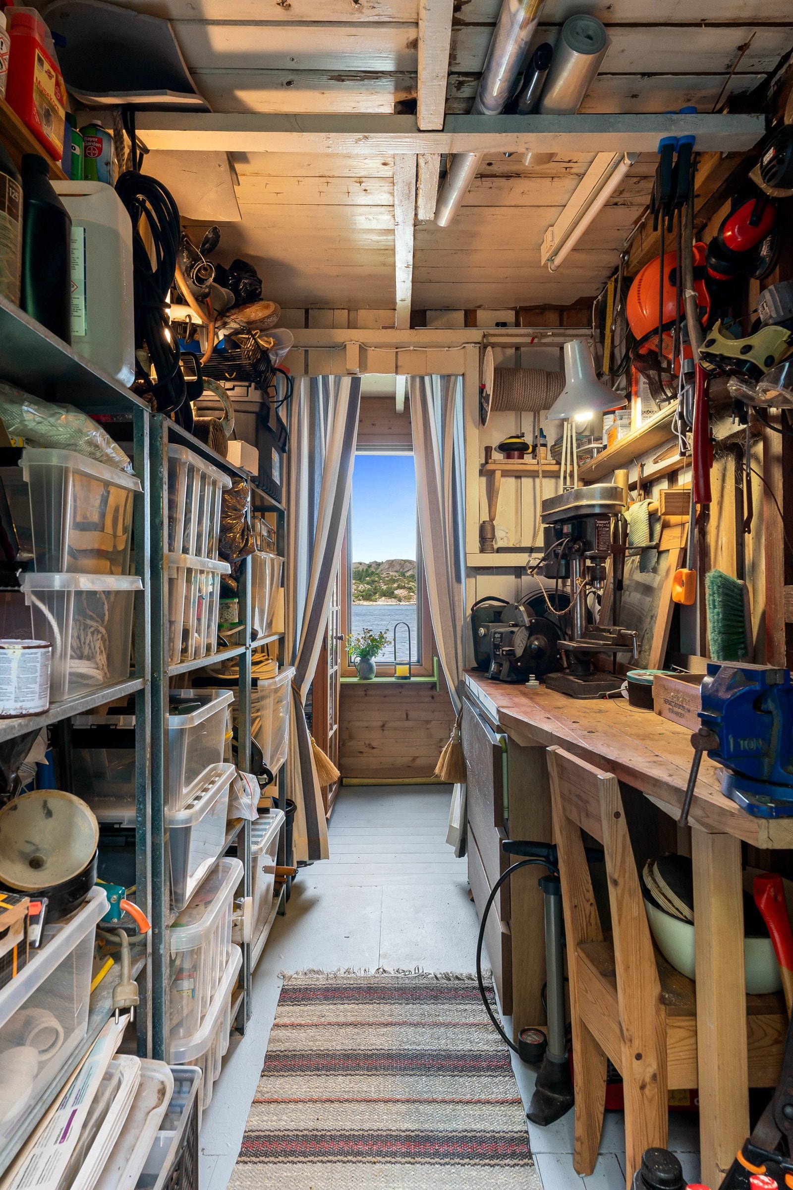 Fra utvendig adkomst kommer man inn til et verksted som kan brukes til oppbevaring eller hobbyrom, rommet har en praktisk hylleløsning langs den ene veggflaten og arbeidsbenk på motsatt veggflate. Galleribilde