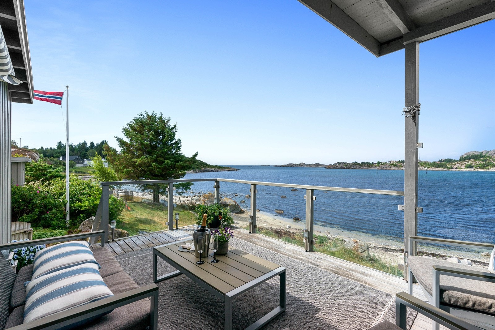 I forkant av hytten er det en vestvendt terrasse med glassrekkverk, noe som gjør at utsikten også kan nytes fra stuen. Galleribilde