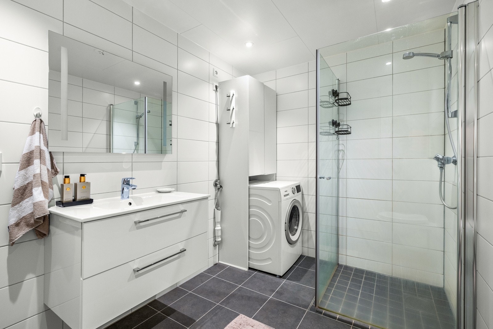 Flislagt baderom med fin løsning og opplegg for vaskemaskin. Galleribilde