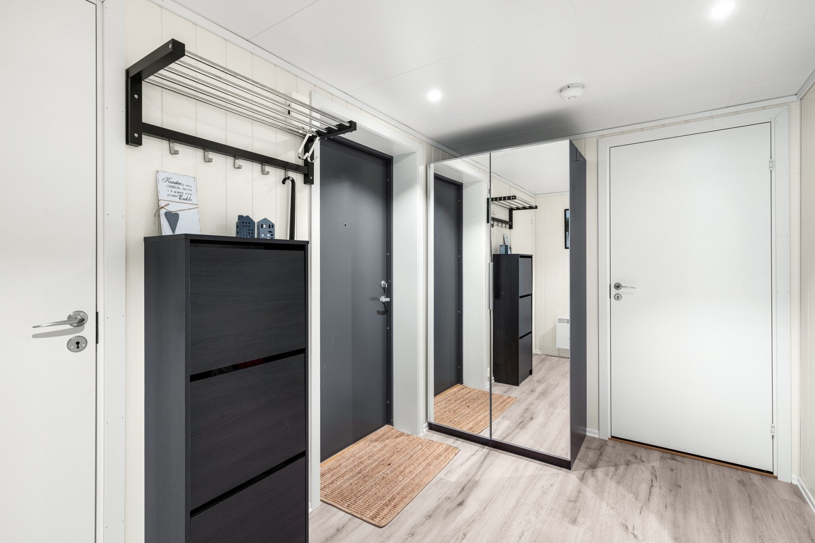 Innbydende entré med garderobeskap og plass knaggrekke, skoskap og speil. Galleribilde