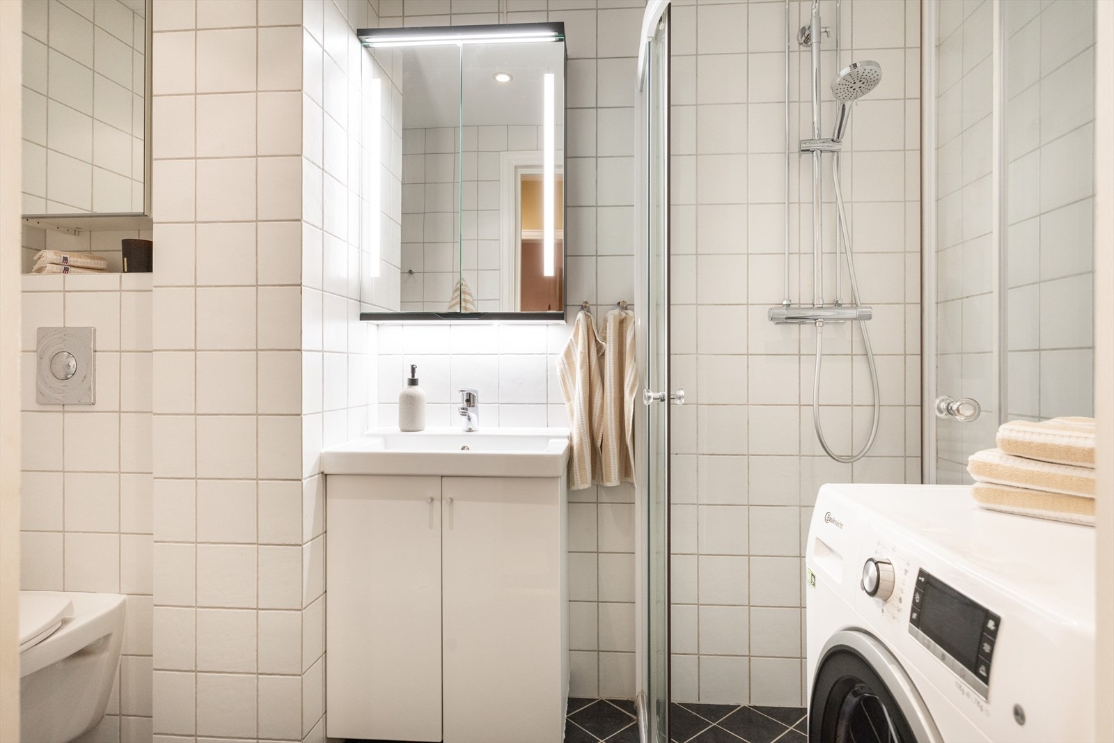 - Baderommet er innredet med dusjhjørne med dusjdører, servant på innredning, speilskap og vegghengt WC - Galleribilde