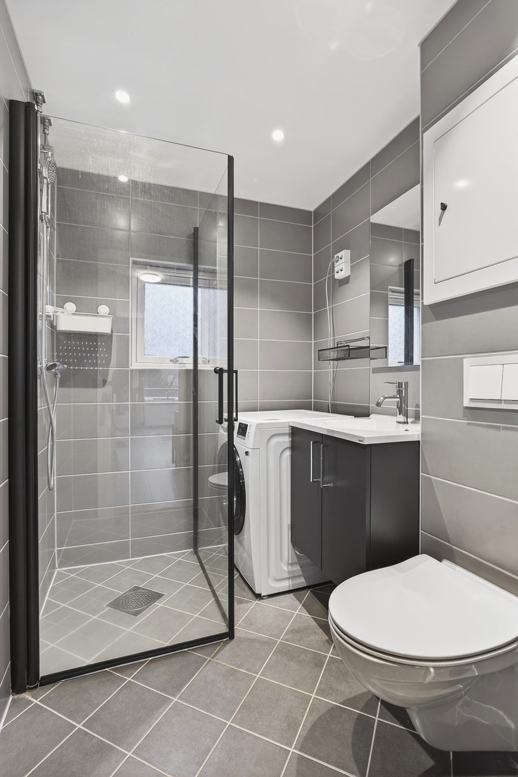 Badet er utstyrt med servant med underskap, speil, dusjhjørne med innfellbare dører og vegghengt toalett. Galleribilde