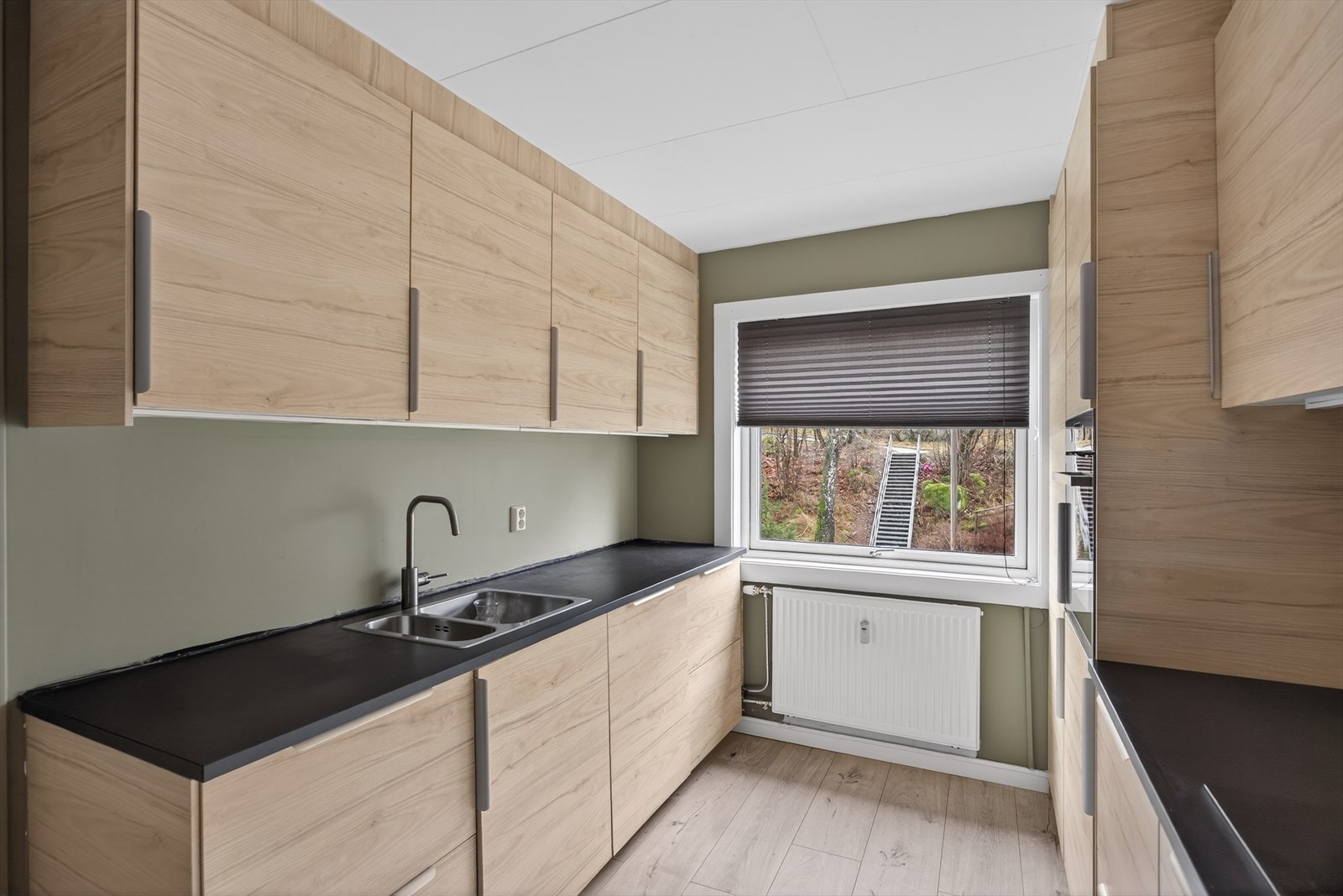 Tidløst uttrykk med under- og overskap i samme utførelse, med sort benkeplate i laminat. Galleribilde