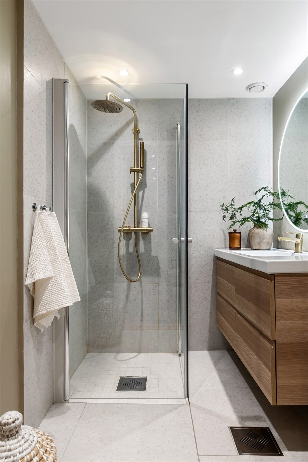 Delikat baderomsinnredning med vegghengt servantskap i eikefiner med skuffeinnredning og heldekkende servant, samt dusjhjørne med innfellbar glassdører og rainshower Galleribilde