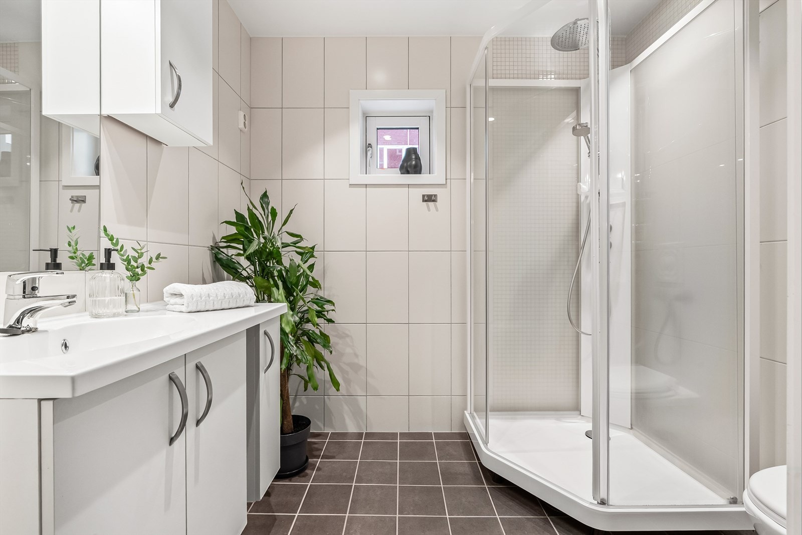 Her fra hovedleilighetens bad. Baderommet er lyst og flislagt, har downlights i himling, elektrisk gulvvarme, vegghengt klosett, dusjkabinett og opplegg for vaskemaskin. I tillegg har rommet et lite vindu. Galleribilde