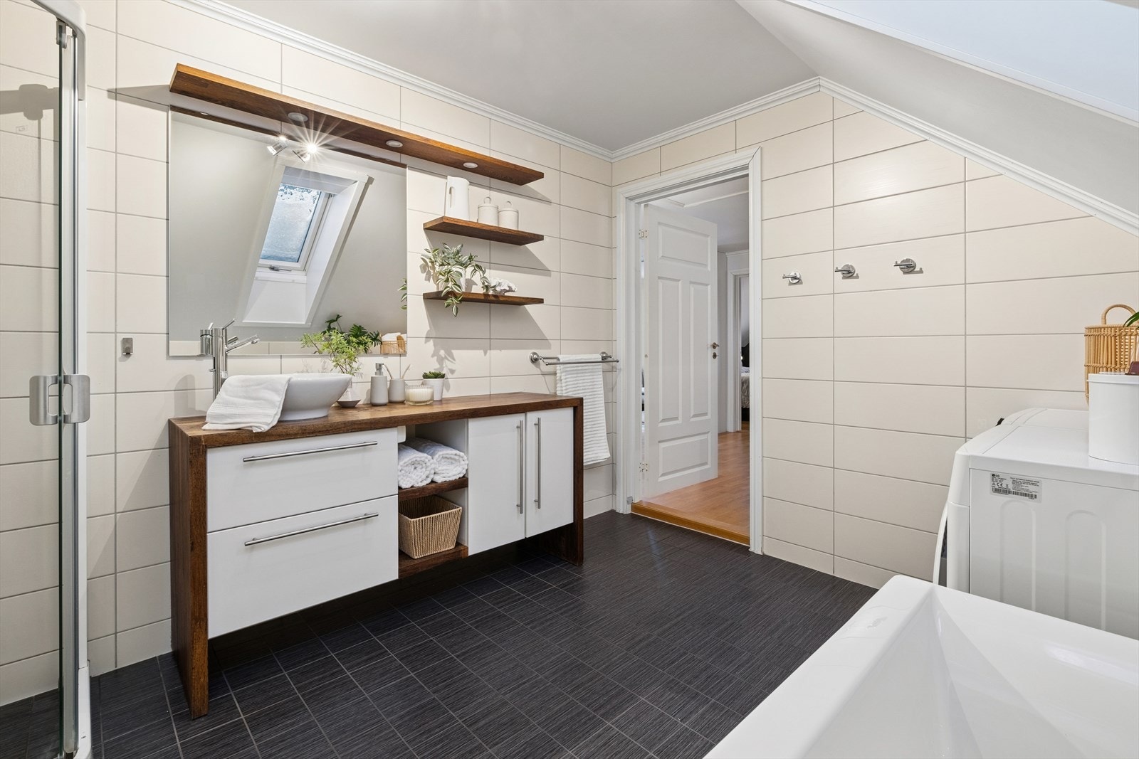 Innredningen inkluderer et benkeskap med glatte fronter, speil over servanten og trehyller på veggen. Galleribilde