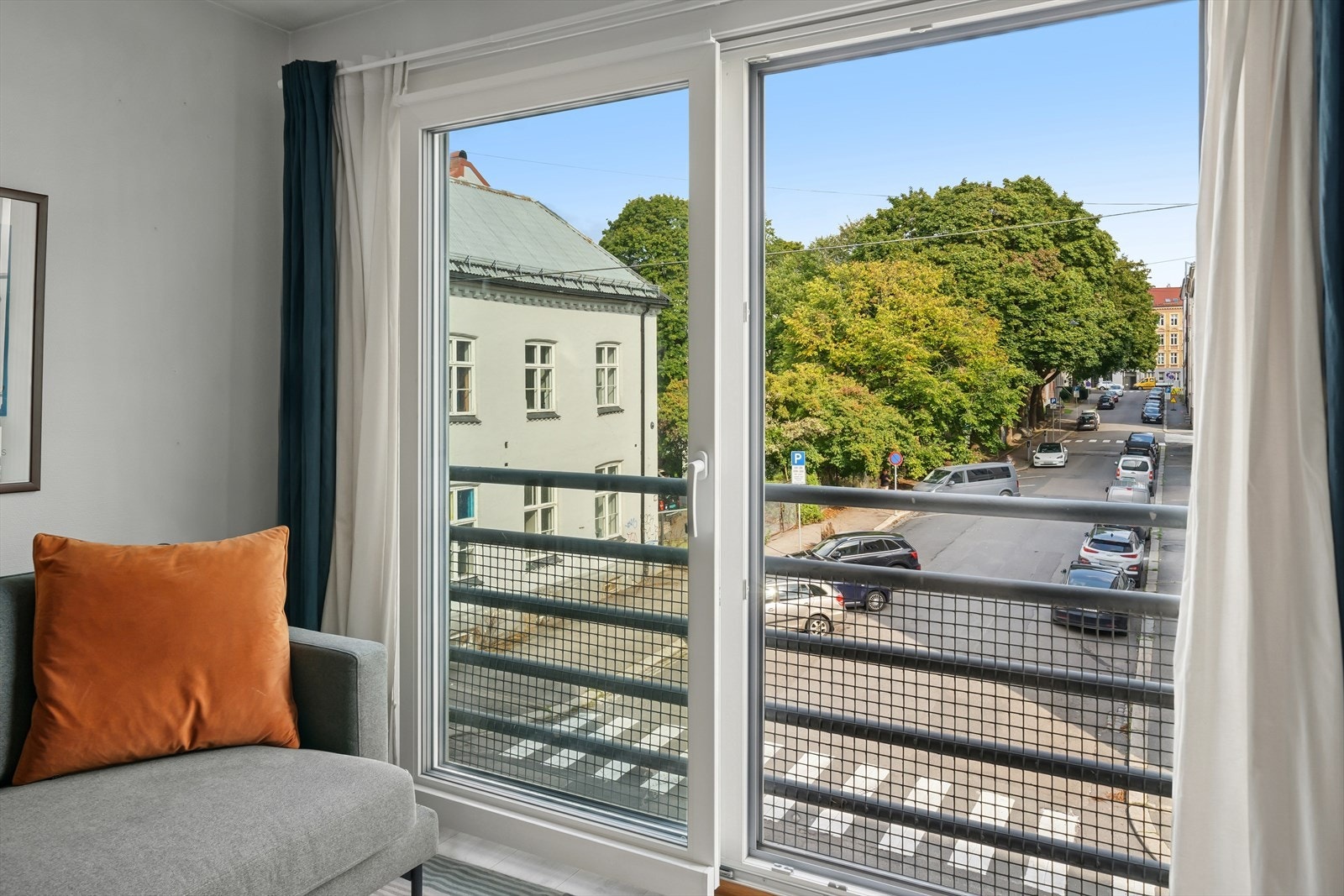 Den franske balkongen vender ut mot en rolig sidegate med utsikt mot et frodig grøntareal. Galleribilde